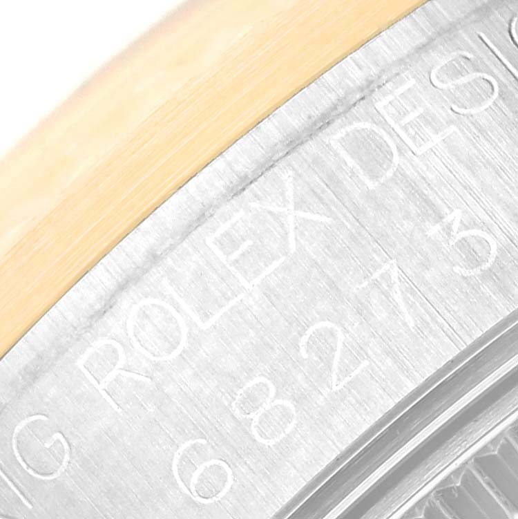 This close-up image shows the edge of the case and part of the bezel of a Mid-Size Rolex watch, featuring engraved text.