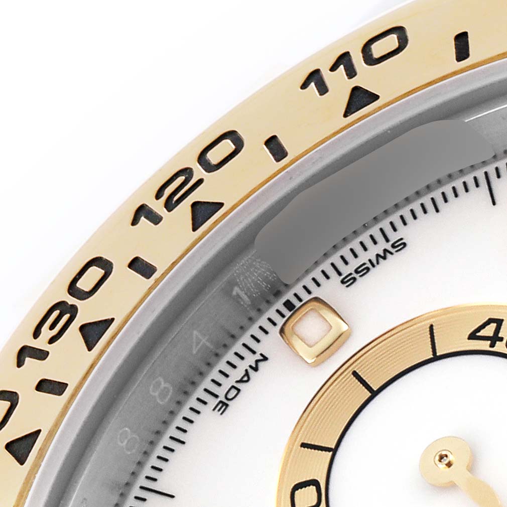 This close-up of the Rolex Daytona 116503 Men's Steel and Gold (two tone) White Dial 116503 Men's Steel and Gold (two tone) White Dial showcases its bezel with engraved numbers and part of the dial with a subdial.