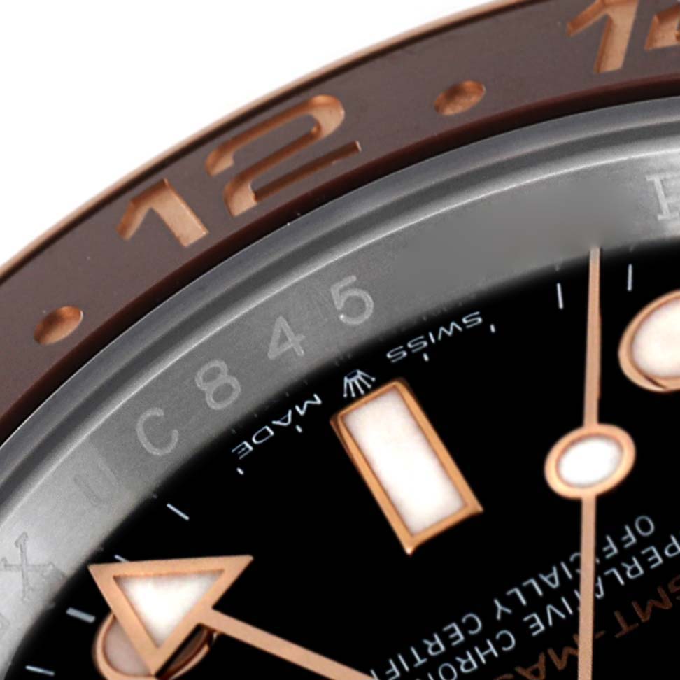 This close-up image of the Rolex GMT-Master 126711 Men's Steel and Gold (two tone) Black Dial 126711 Men's Steel and Gold (two tone) Black Dial watch shows part of the bezel, dial, and some hour markers.