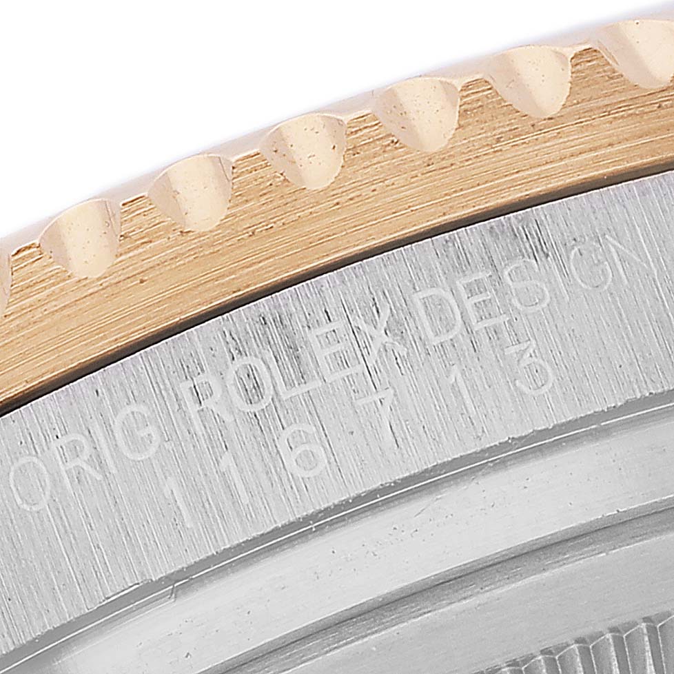 This close-up image shows the edge of the bezel and engraved text on the case of a Rolex GMT-Master 116713 Men's Steel and Gold (two tone) Black Dial 116713 Men's Steel and Gold (two tone) Black Dial watch.