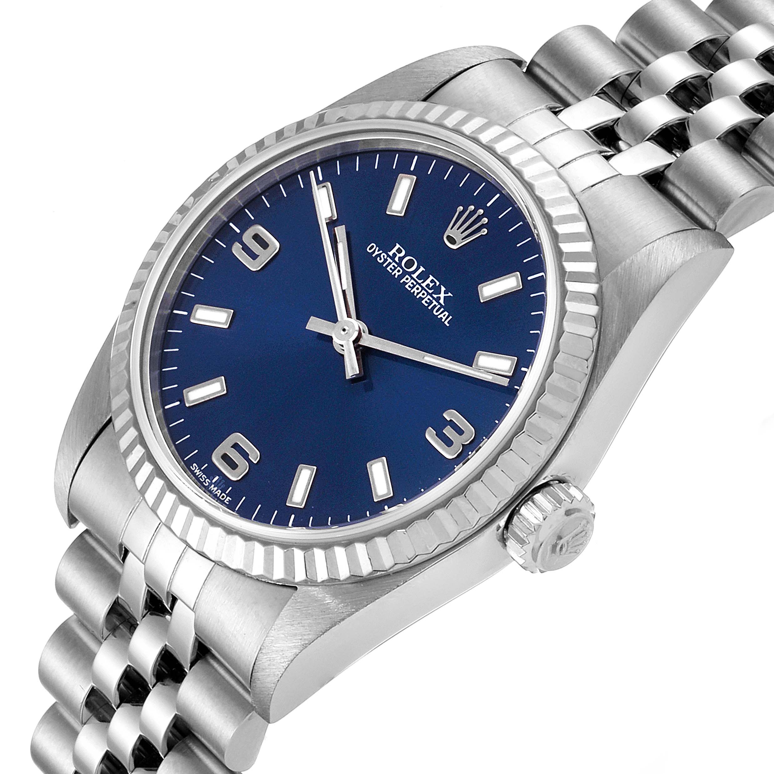 The image shows a mid-size Rolex Oyster Perpetual watch at a slight angle, highlighting its blue dial, silver bracelet, and crown.