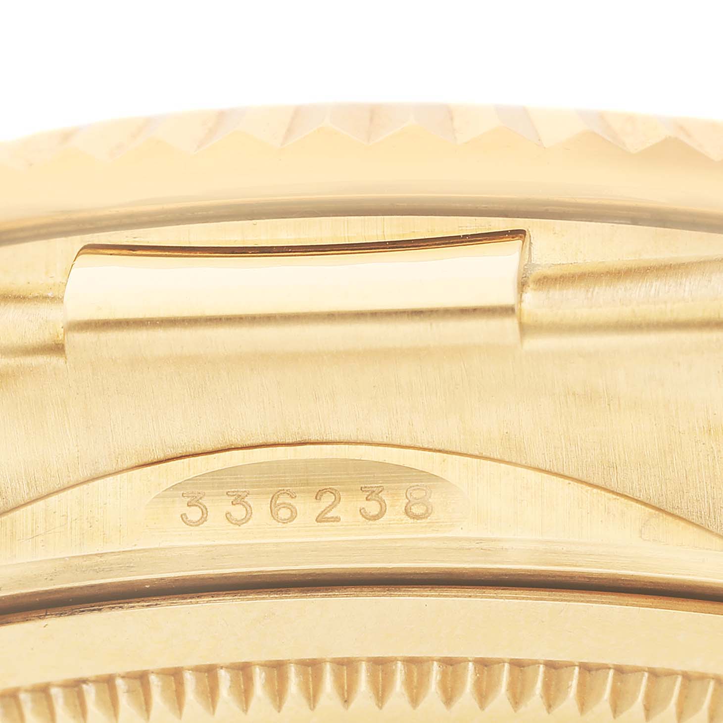 The image shows a close-up of the side with the serial number of a Rolex Sky-Dweller 336238 Men's Yellow Gold White Dial watch, focusing on its gold detailing.