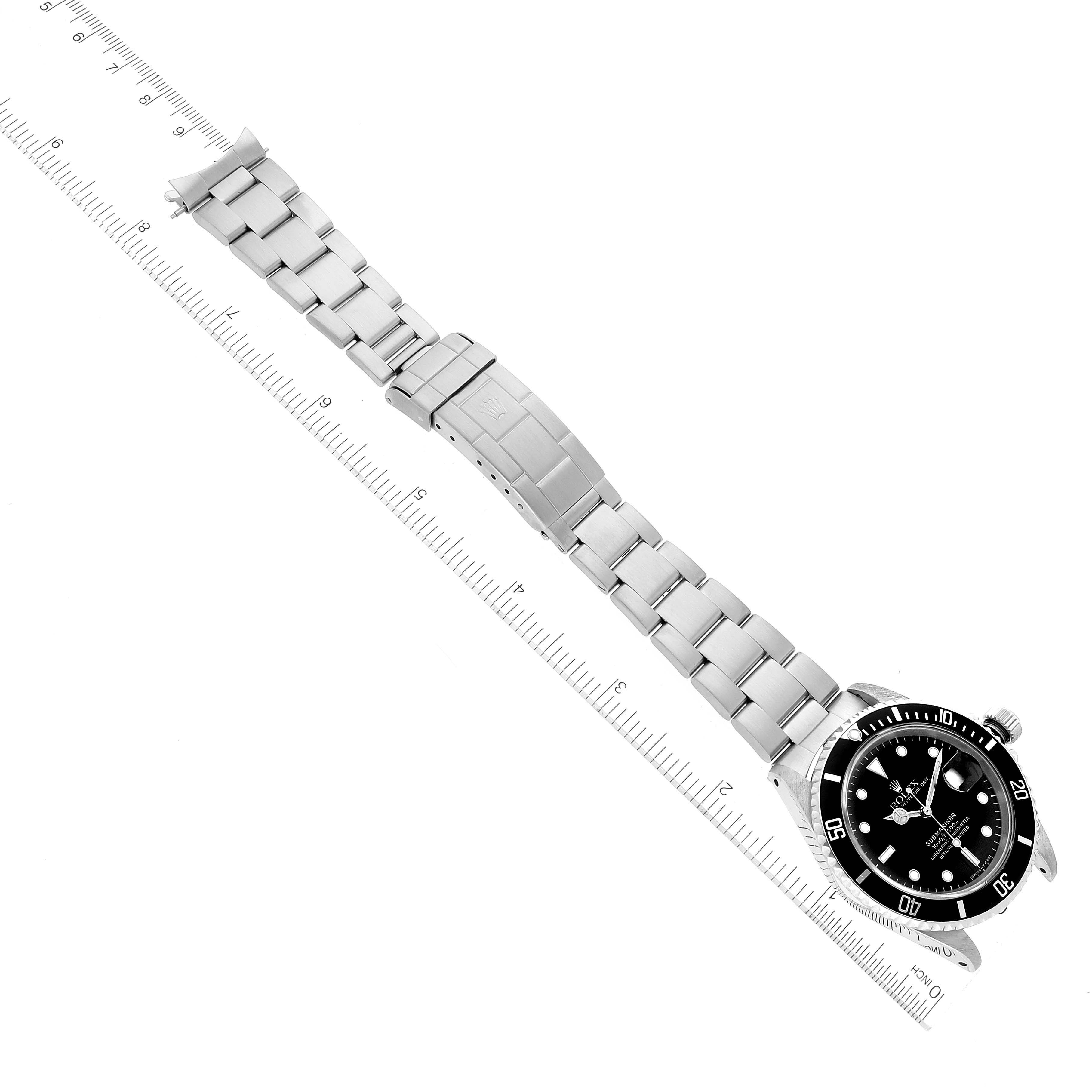 The Rolex Submariner 16610 Men's Stainless Steel Black Dial 16610 Men's Stainless Steel Black Dial watch is displayed vertically showing its face, bezel, crown, and metal bracelet with a ruler for scale.