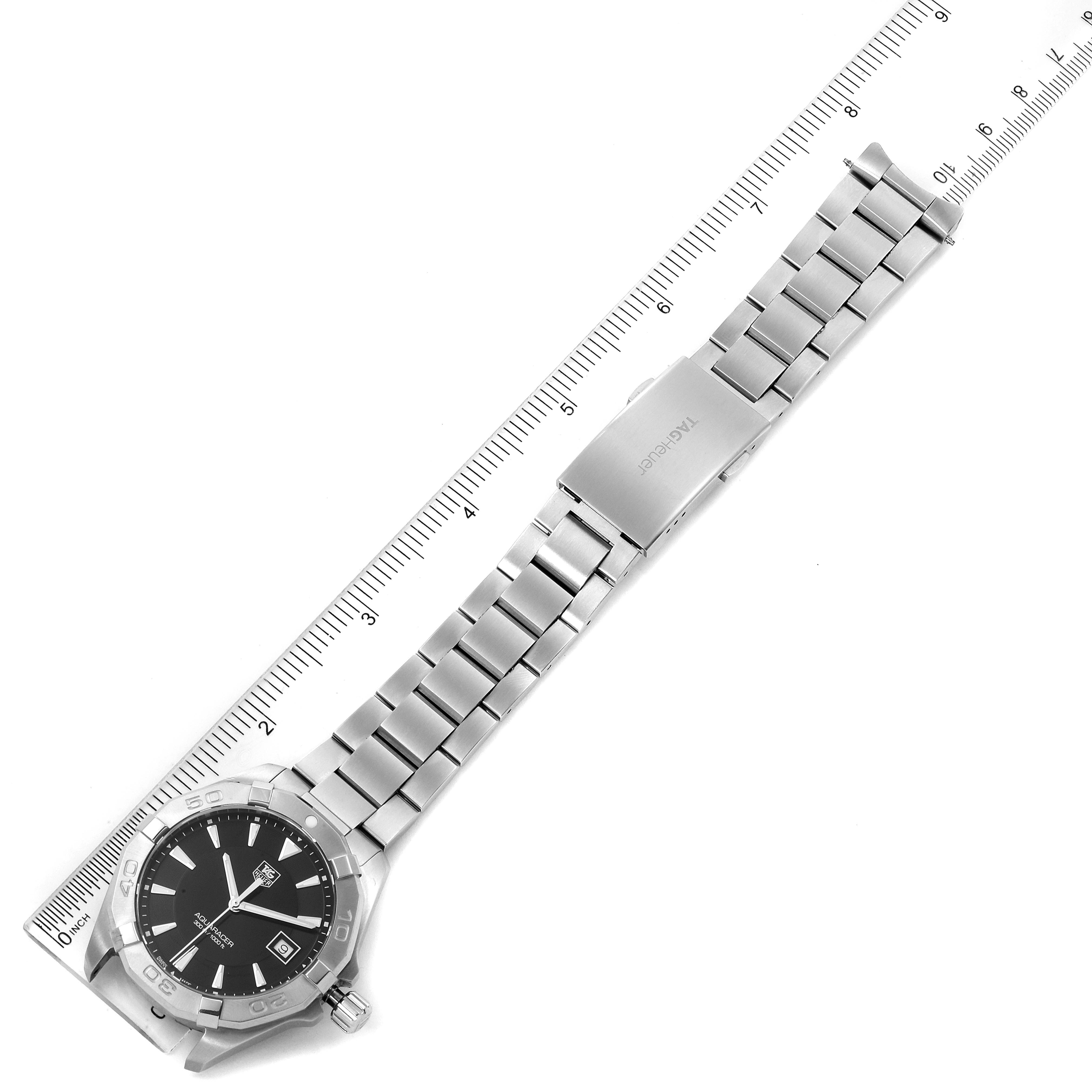 The image shows a Tag Heuer Aquaracer WAY1110.BA0928 Men
s Stainless Steel Black Dial WAY1110.BA0928 Men
s Stainless Steel Black Dial watch laid flat next to a ruler, highlighting its full strap and face from a top-down angle.
