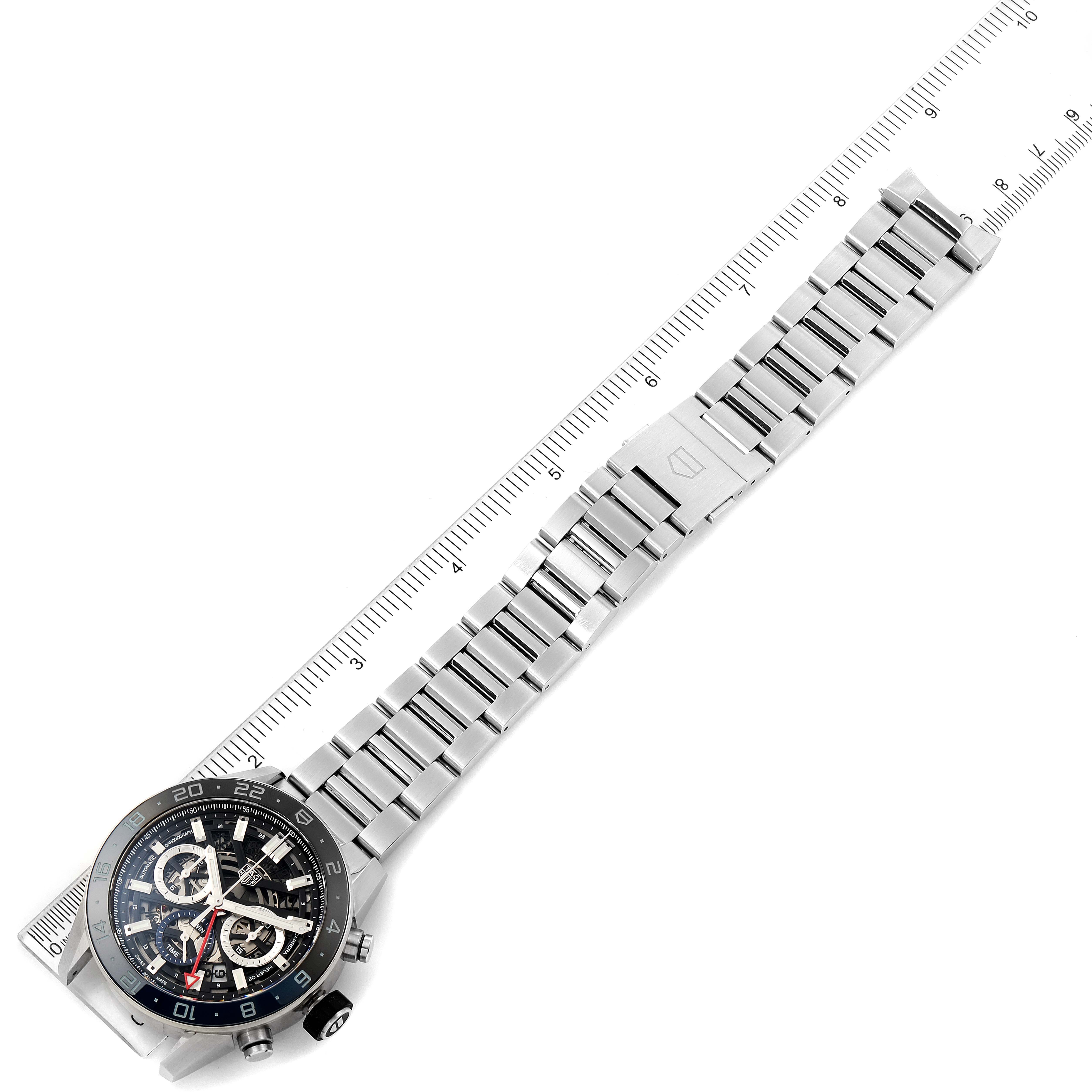 The image shows a top-down view of a Tag Heuer Carrera CBG2A1Z.BA0658 Men
s Stainless Steel Black Dial CBG2A1Z.BA0658 Men
s Stainless Steel Black Dial watch displaying the face and metal bracelet alongside a ruler for measurement.
