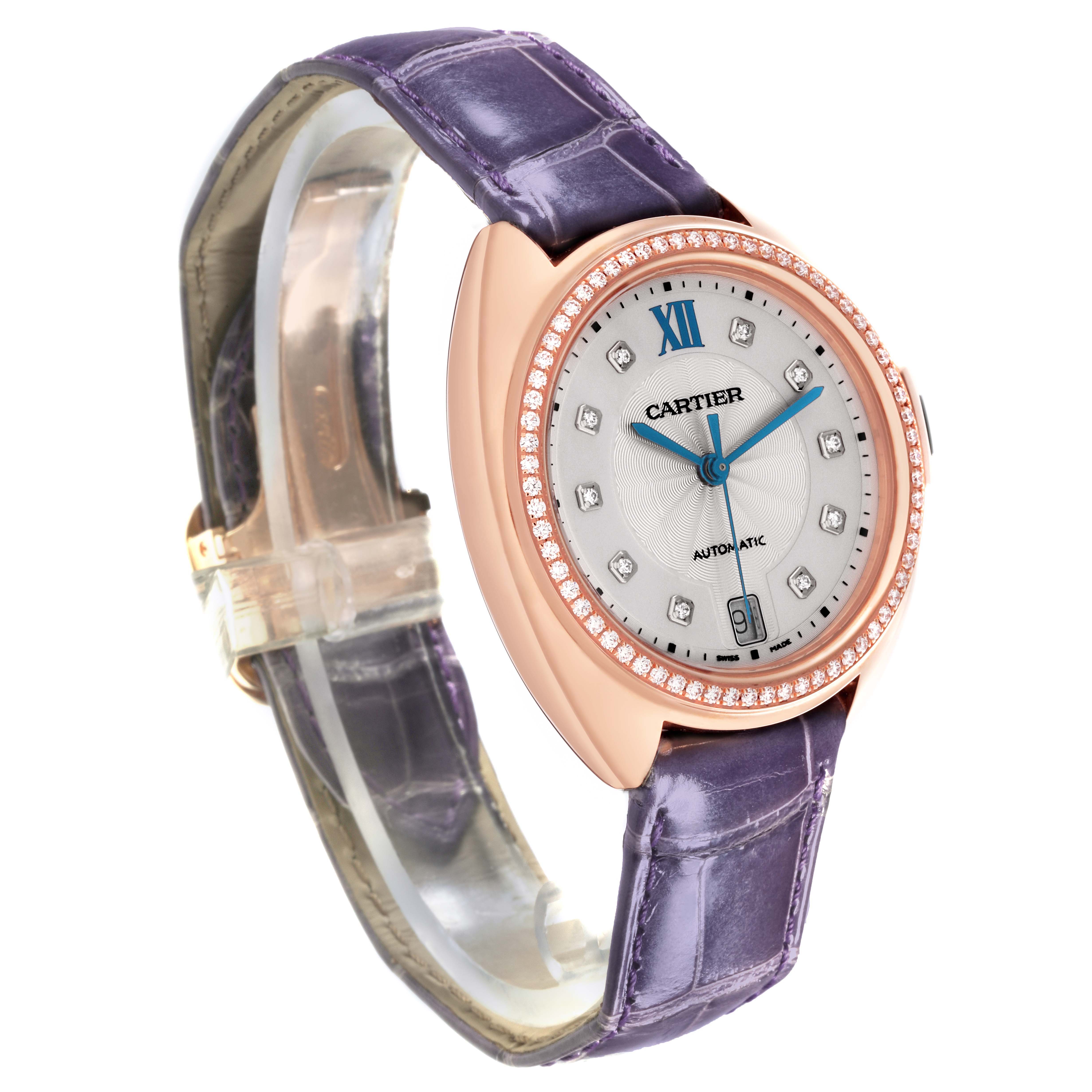 The Cartier Clé watch is shown at a three-quarter angle, highlighting the face, diamond bezel, case, and purple strap.