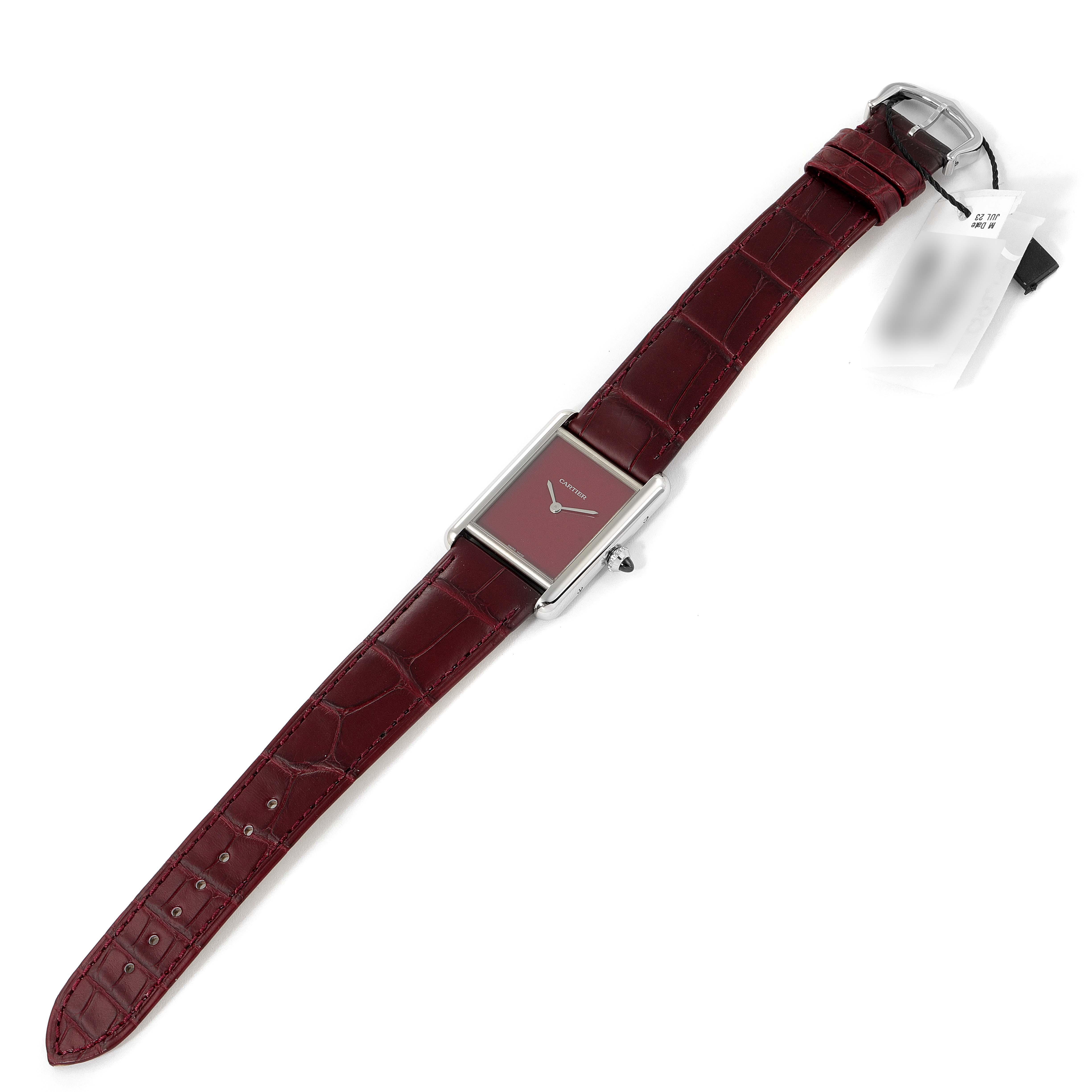 The Cartier Tank Must WSTA0054 Women's Stainless Steel Red Dial WSTA0054 Women's Stainless Steel Red Dial watch is shown laid flat, highlighting its rectangular dial, burgundy leather strap, and silver buckle.