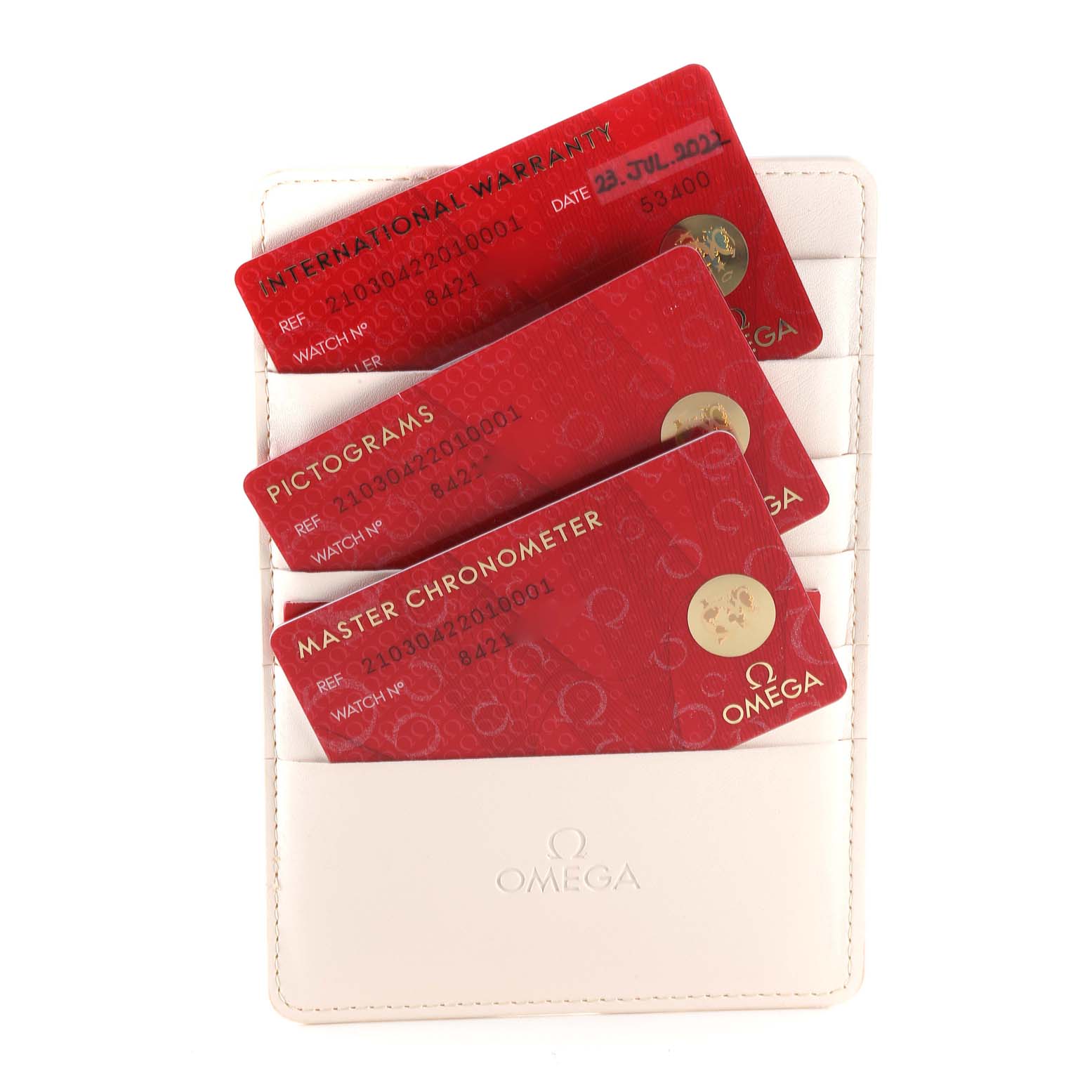 The image shows three red cards (International Warranty, Pictograms, Master Chronometer) in an Omega wallet for the Seamaster model.
