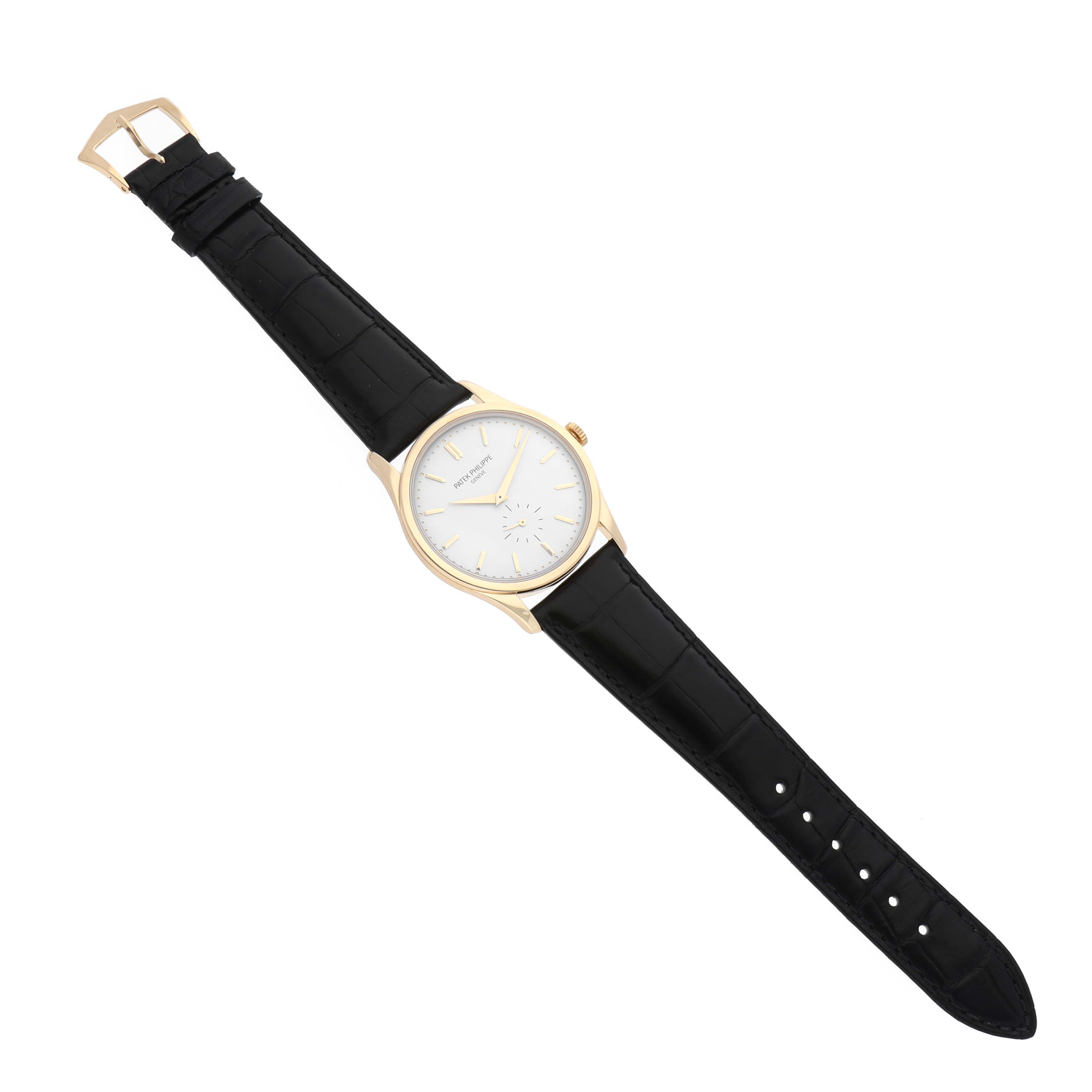 The image shows a full Patek Philippe Calatrava 5196J Men's Yellow Gold Silver Dial 5196J Men's Yellow Gold Silver Dial watch with a black leather strap, golden case, and white dial, viewed from above.