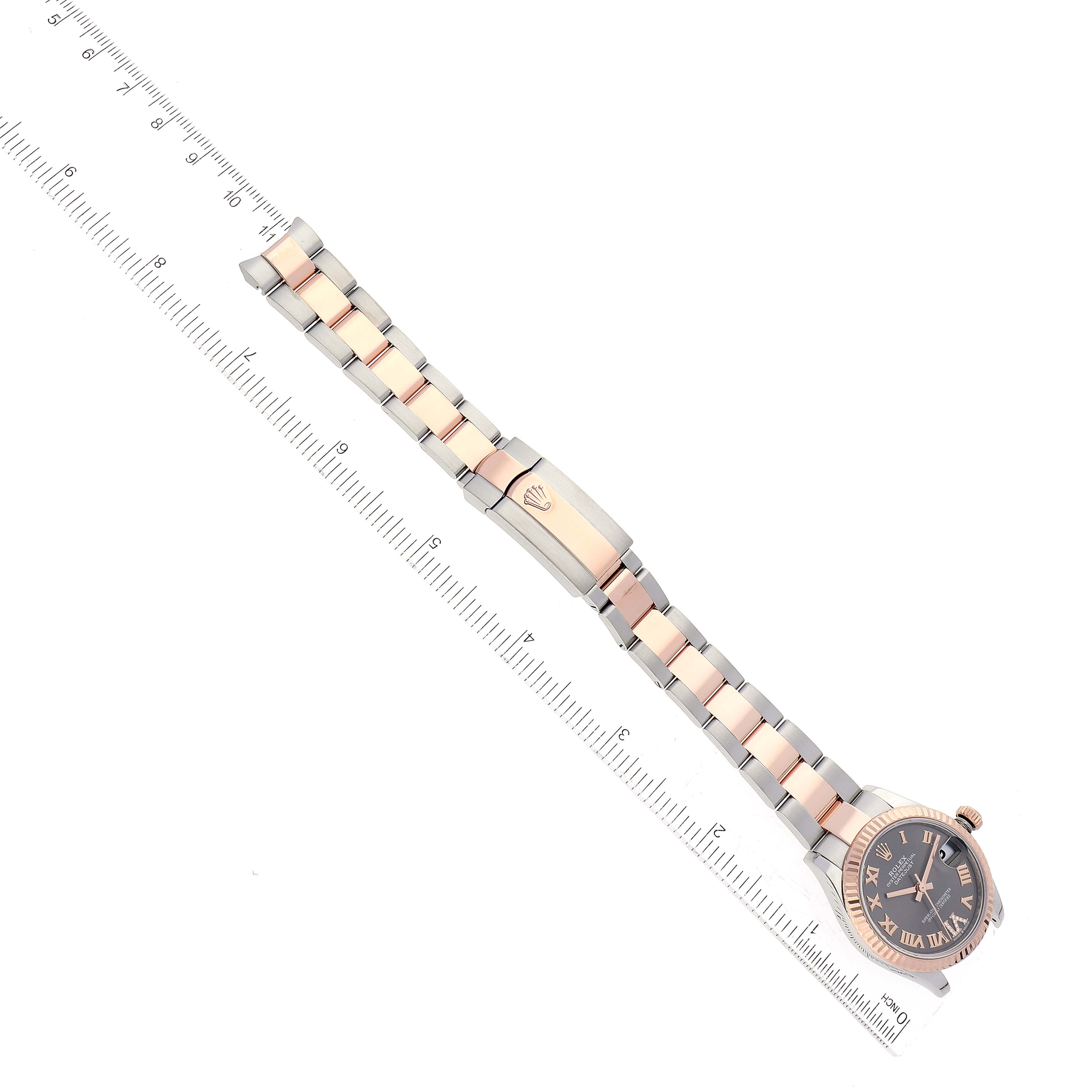 The Rolex Mid-Size 278271 Women's Steel and Gold (two tone) Grey Dial 278271 Women's Steel and Gold (two tone) Grey Dial watch is shown from a top-down angle with its entire band and face visible, alongside a ruler for scale.
