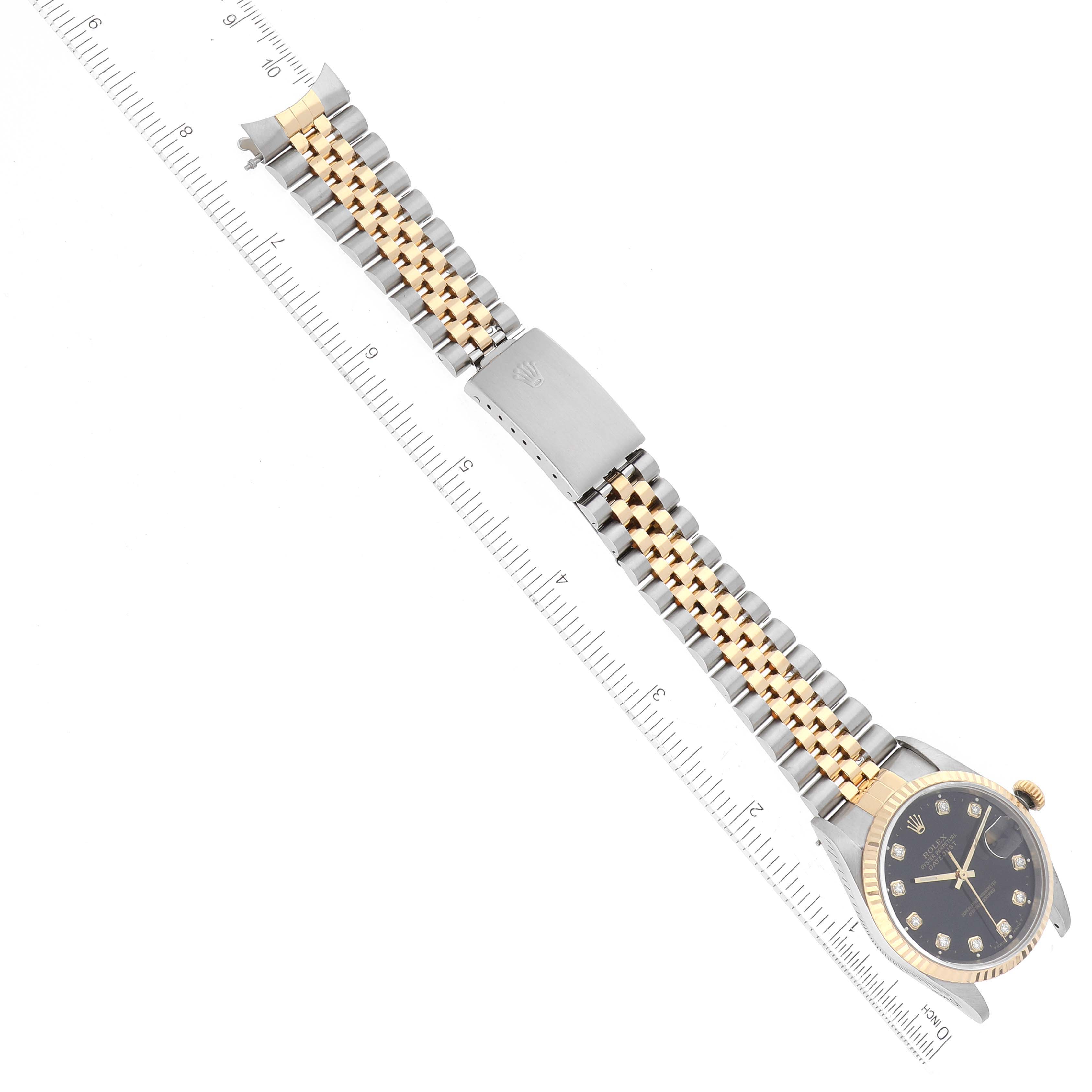 The image shows a Rolex Datejust 16233 Men's Steel and Gold (two tone) Black Dial 16233 Men's Steel and Gold (two tone) Black Dial watch fully extended with its face, bezel, and two-tone bracelet visible, measured against a ruler.