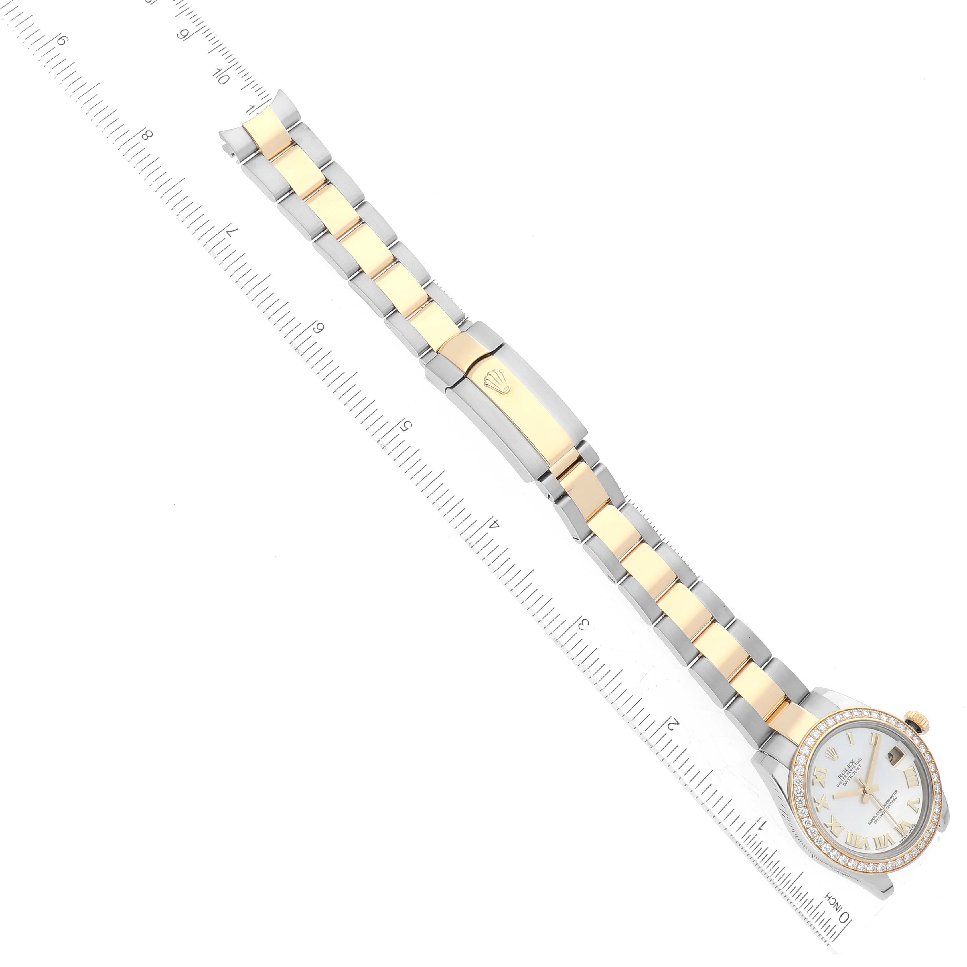 This top-view image shows the entire Rolex Mid-Size 178383 Women
s Steel and Gold (two tone) Mother of Pearl Dial 178383 Women
s Steel and Gold (two tone) Mother of Pearl Dial watch, including the dial, bezel, bracelet, and clasp, alongside a ruler for scale.