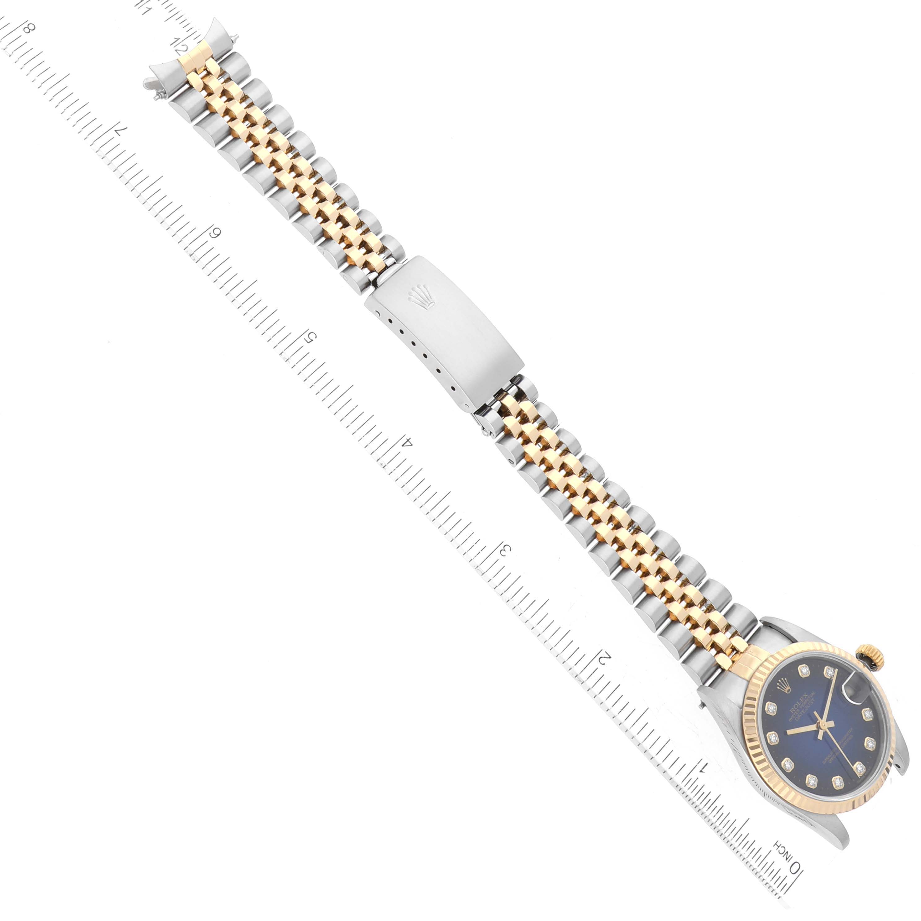 The image shows a top-down view of a Rolex Mid-Size 68273 Women's Steel and Gold (two tone) Blue Dial 68273 Women's Steel and Gold (two tone) Blue Dial model watch with the full strap and part of a ruler next to it.