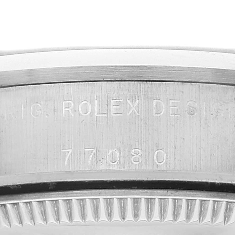 The image shows the side of a Rolex Mid-Size 77080 Women's Stainless Steel Blue Dial 77080 Women's Stainless Steel Blue Dial model watch with engraving and part of the bezel.
