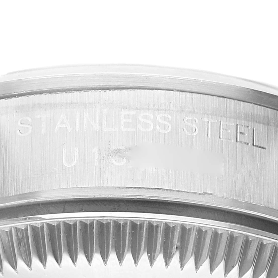 The image shows a close-up of the side of the bezel and case of a Rolex Oyster Perpetual 67180 Women's Stainless Steel Blue Dial 67180 Women's Stainless Steel Blue Dial model, highlighting the engraved text "STAINLESS STEEL."