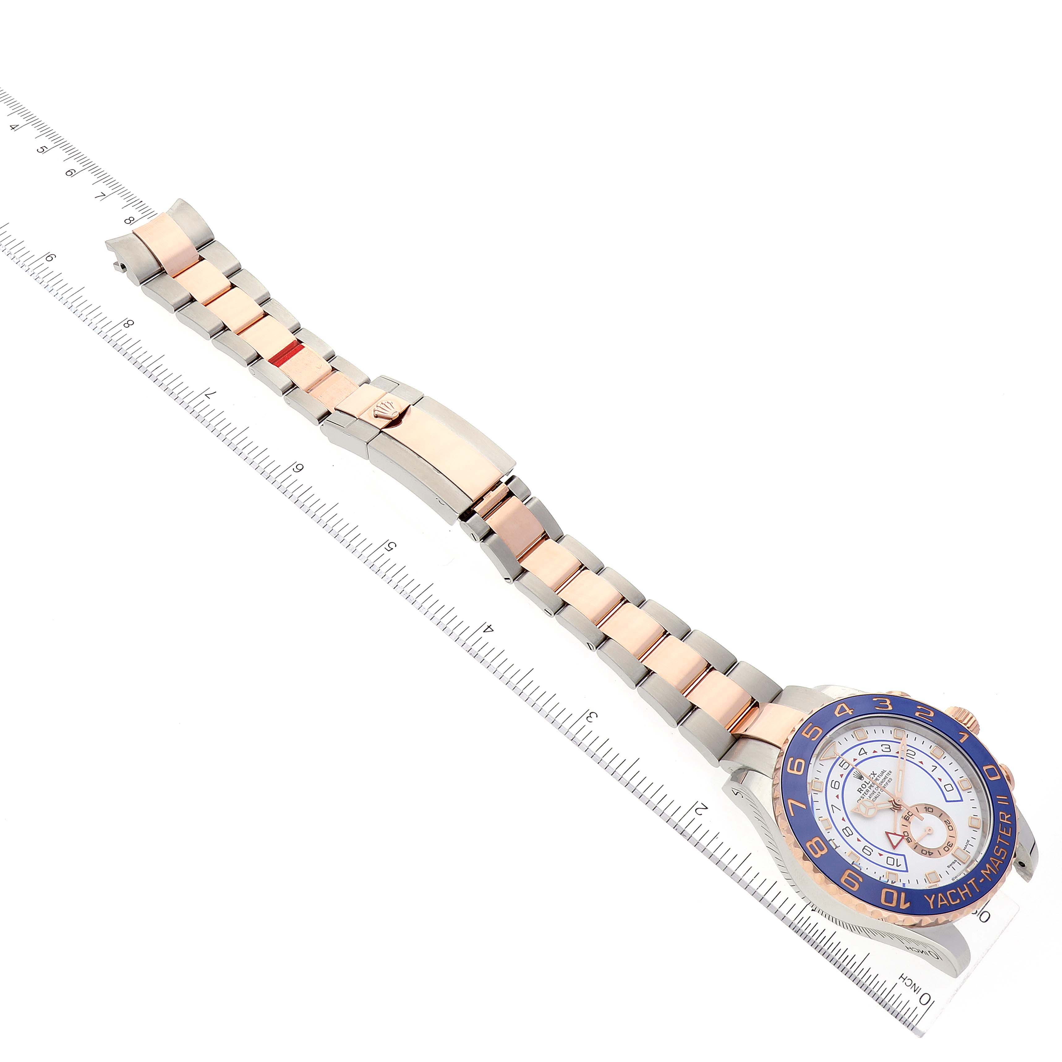 The image shows a Yacht-Master Rolex watch laid flat with the face, bracelet, and clasp visible, aligned with a ruler.