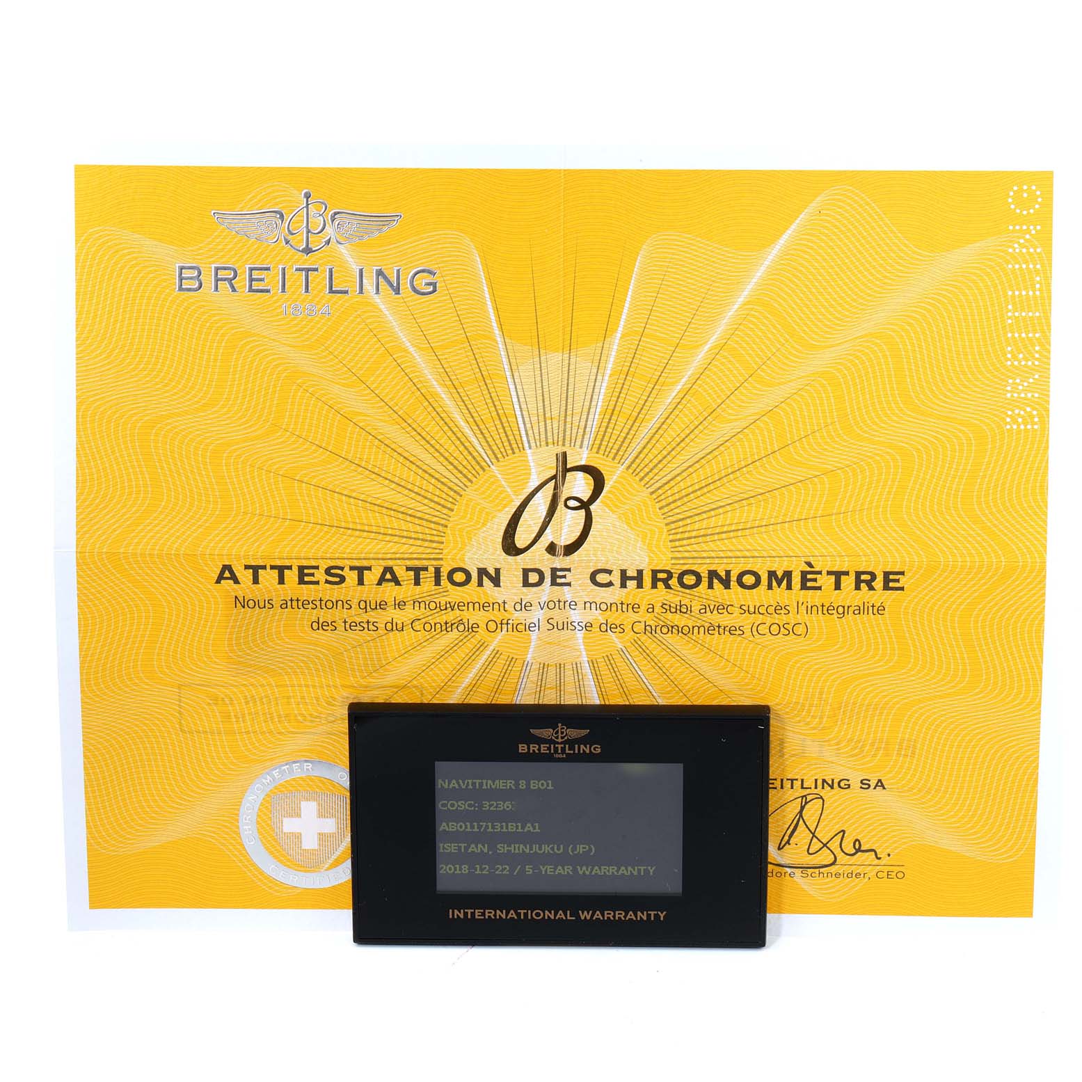 The image shows an official Breitling Navitimer 8 B01 warranty card placed on top of a yellow certification document.