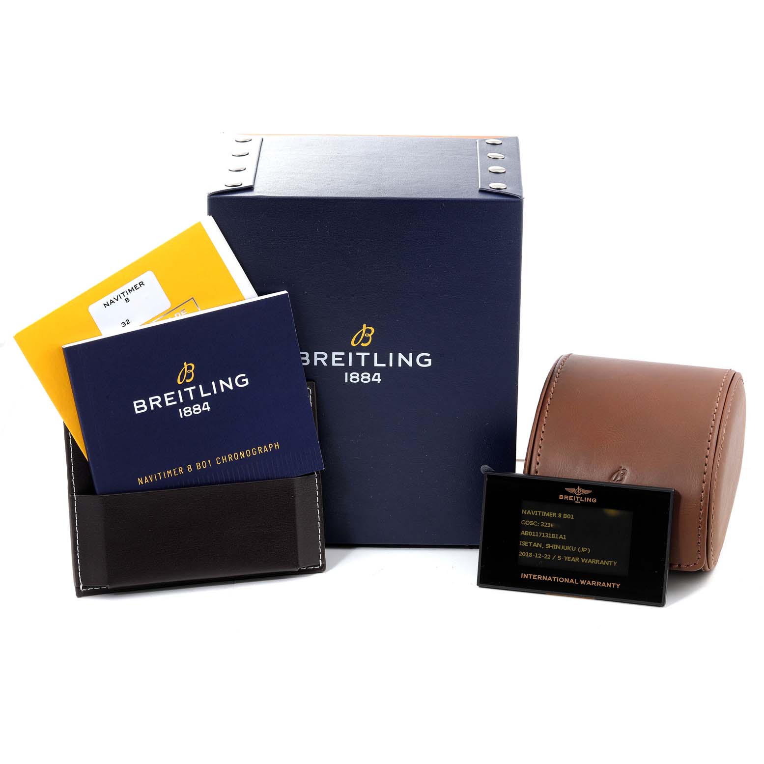 The image shows a Breitling Navitimer watch box, manuals, a warranty card, and a leather travel case, neatly arranged together.