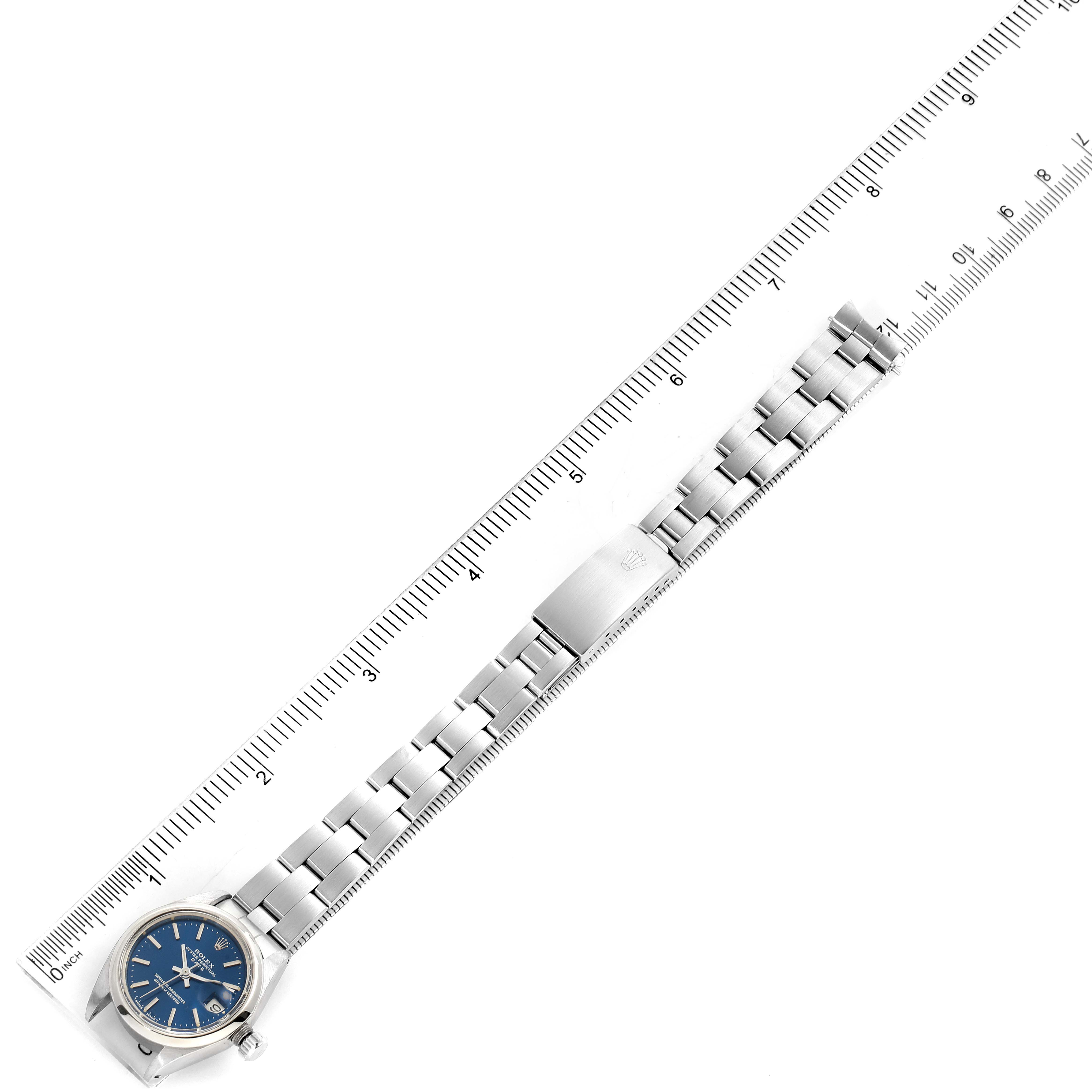 This image displays a Rolex Date 6916 Women's Stainless Steel Blue Dial 6916 Women's Stainless Steel Blue Dial model watch from a top-down angle, showing the watch face, bracelet, and clasp alongside a ruler.