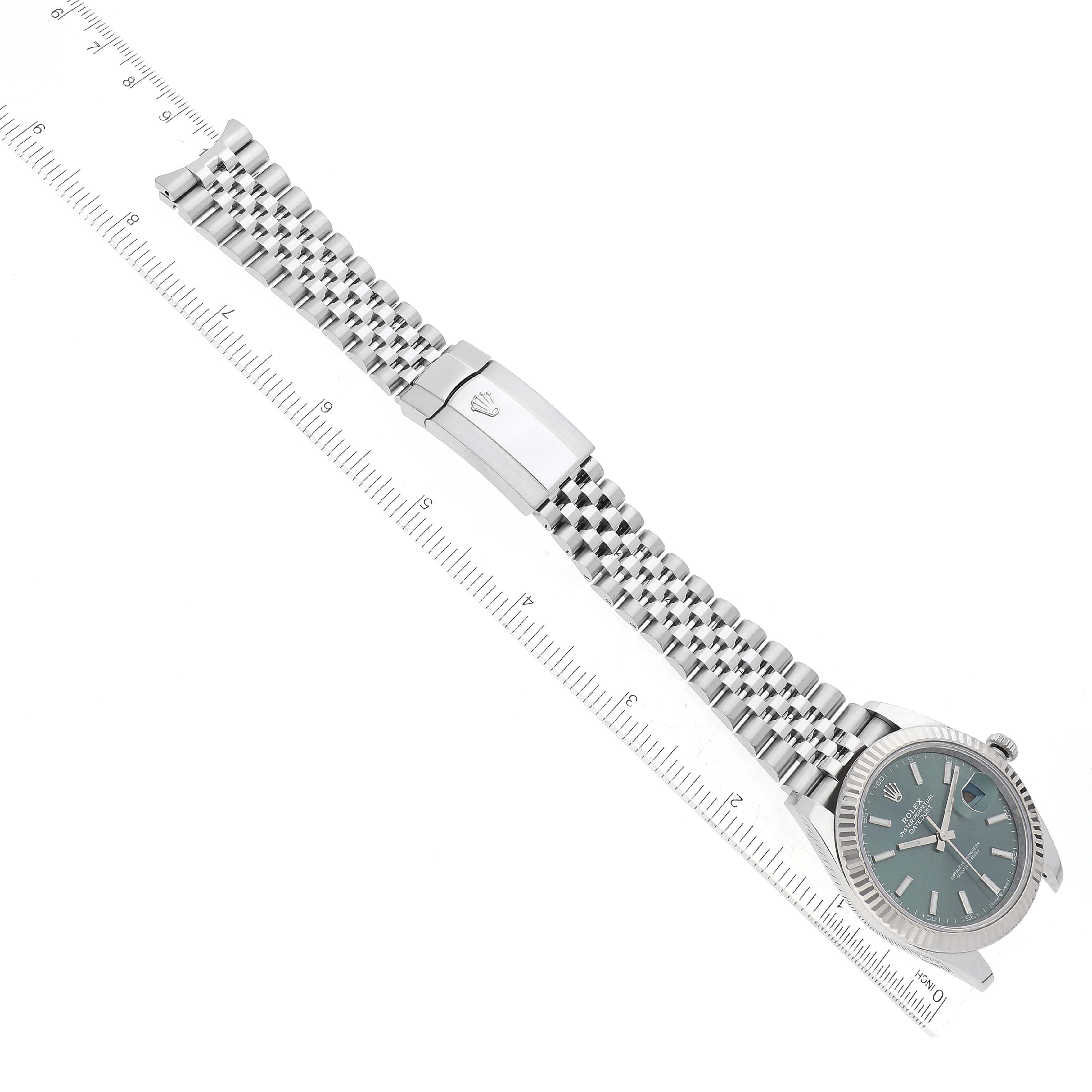 The image shows a Rolex Datejust 41 126334 Men
s Stainless Steel Green Dial 126334 Men
s Stainless Steel Green Dial watch laying flat with a ruler next to it.