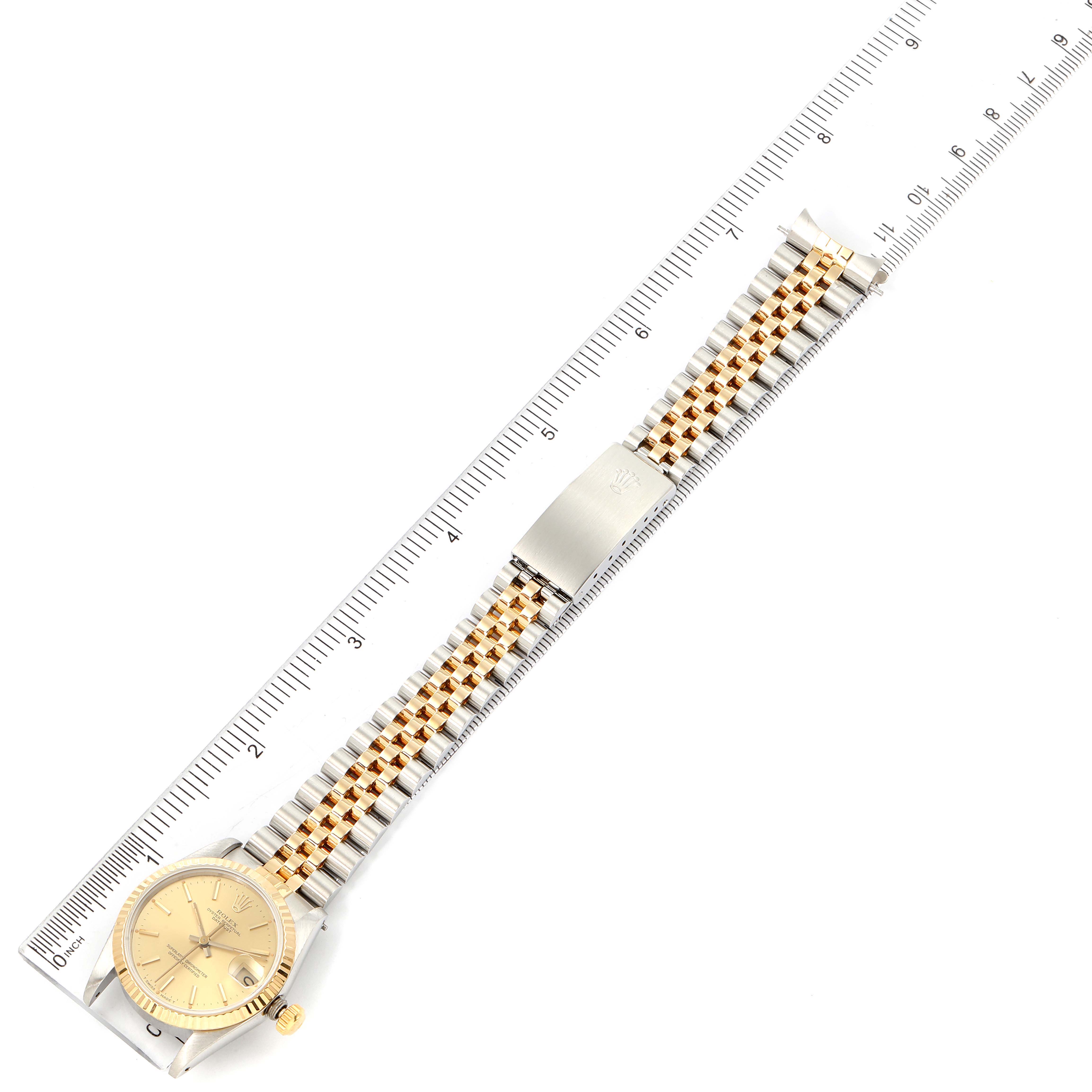 The image shows a top view of a Rolex Mid-Size 68273 Women
s Steel and Gold (two tone) Champagne Dial 68273 Women
s Steel and Gold (two tone) Champagne Dial watch with a two-tone bracelet and a ruler measuring its length.
