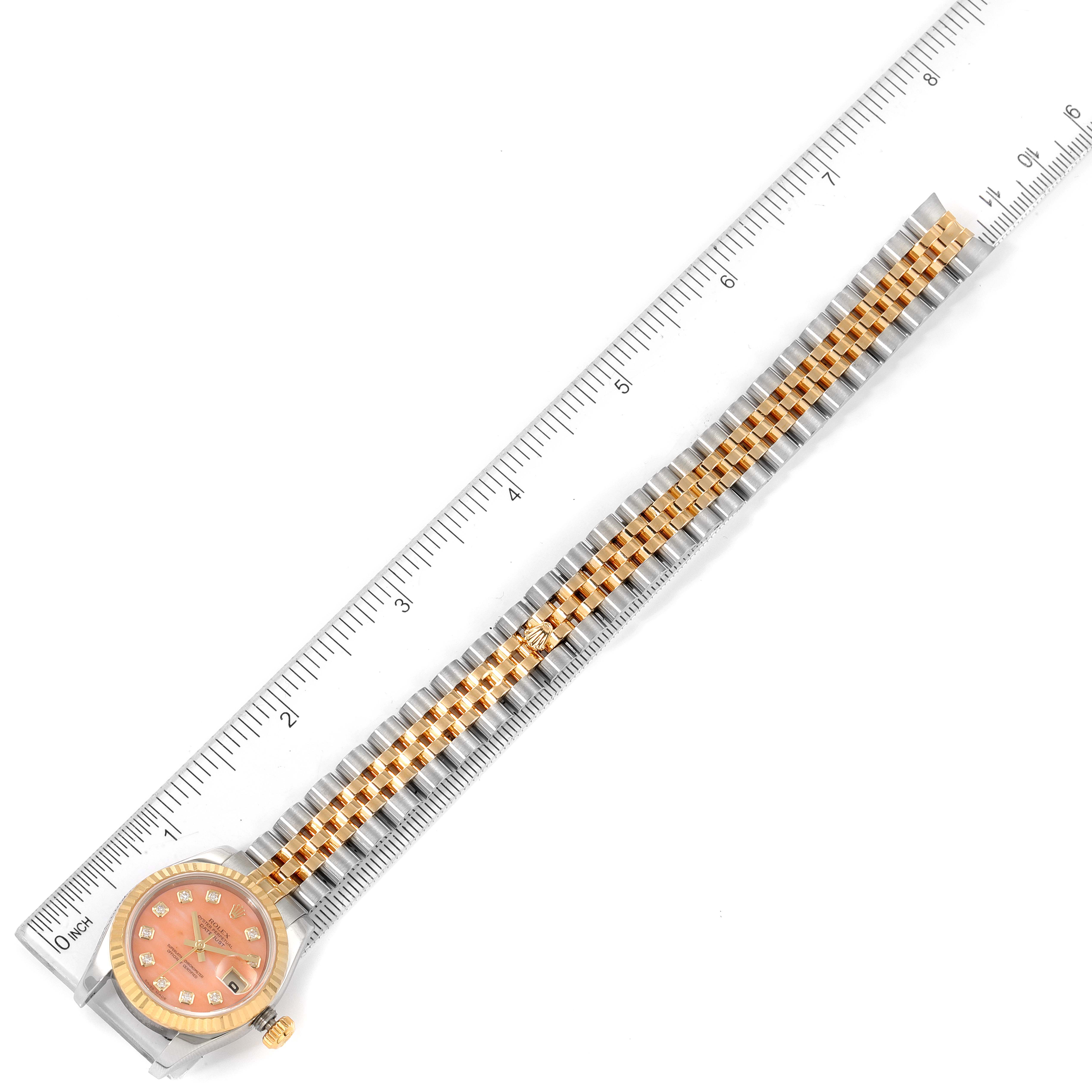 The Rolex Datejust 179173 Women's Steel and Gold (two tone) Pink Dial 179173 Women's Steel and Gold (two tone) Pink Dial watch is shown from a top-down angle with a ruler for scale.