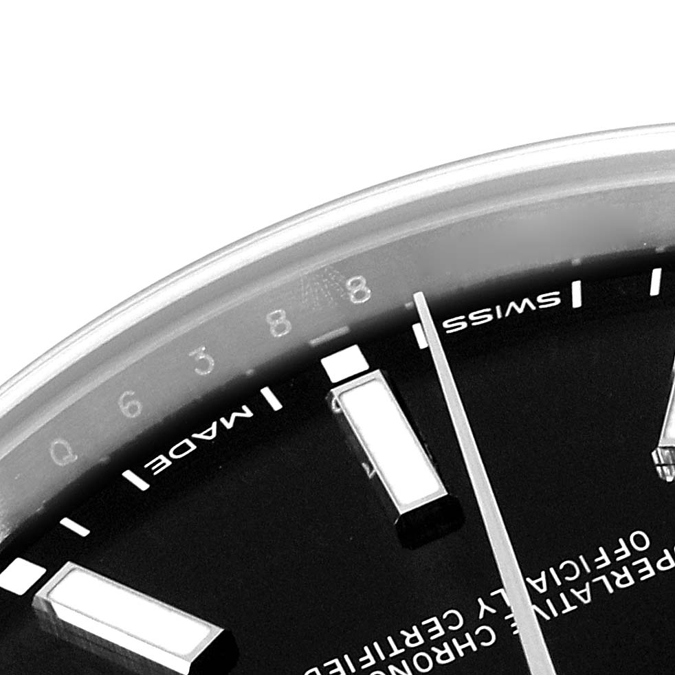This image shows a close-up of the dial of a Rolex Oyster Perpetual 114300 Men
s Stainless Steel Black Dial 114300 Men
s Stainless Steel Black Dial watch, focusing on the hour markers and part of the text.