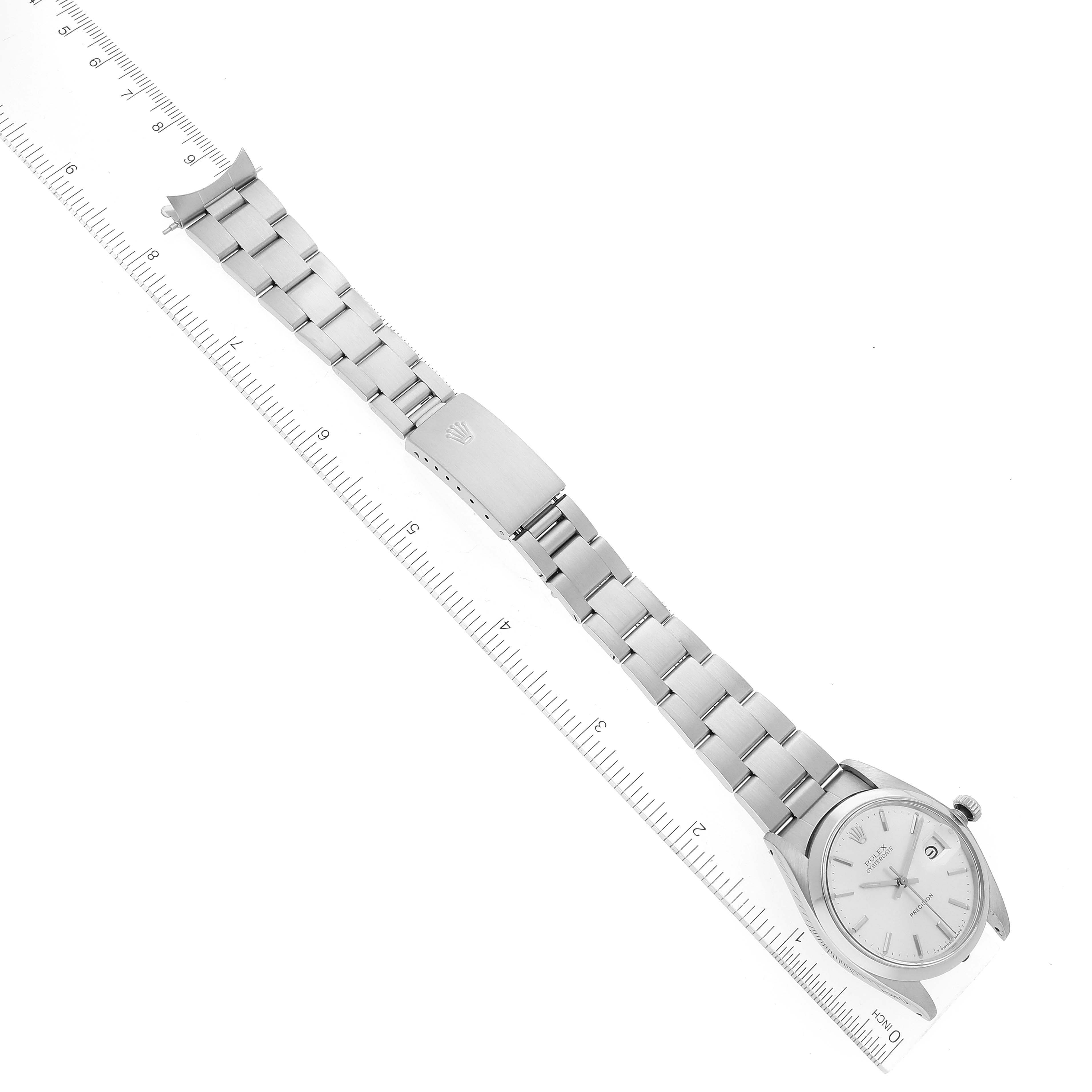 The Vintage Collection Rolex watch is shown laying flat; visible parts include the face, bezel, bracelet, clasp, and crown with a ruler for scale.