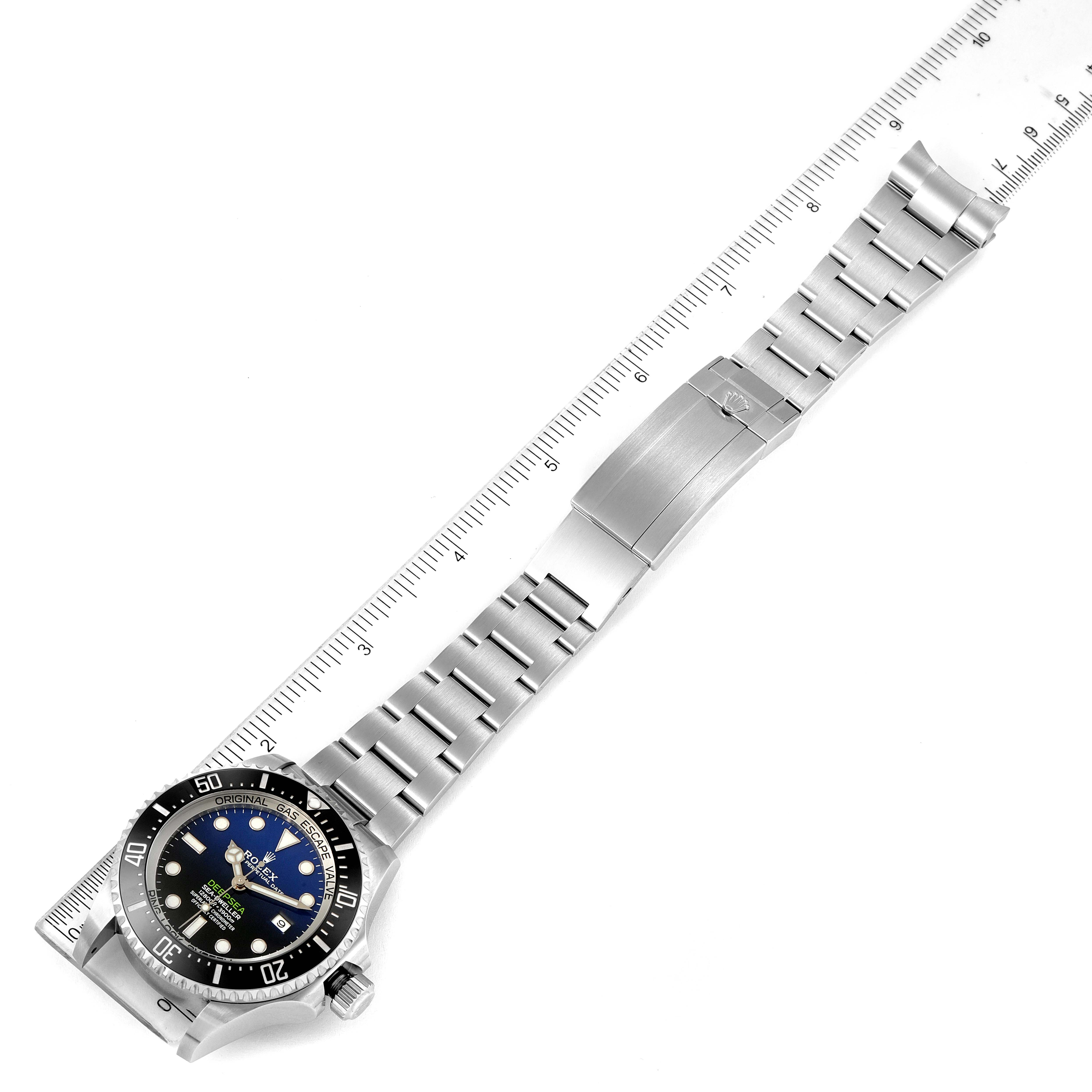 The image shows a top-down view of a Rolex Sea-Dweller 126660 Men
s Stainless Steel Blue Dial 126660 Men
s Stainless Steel Blue Dial watch, highlighting its bezel, dial, and metal bracelet with a clasp alongside a ruler.