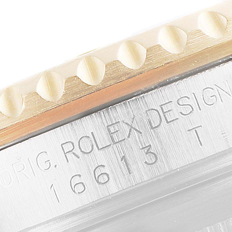The image shows a close-up of the Rolex Submariner 16613 Men
s Steel and Gold (two tone) Grey Dial 16613 Men
s Steel and Gold (two tone) Grey Dial model
s engraved serial number and part of the watch bezel.