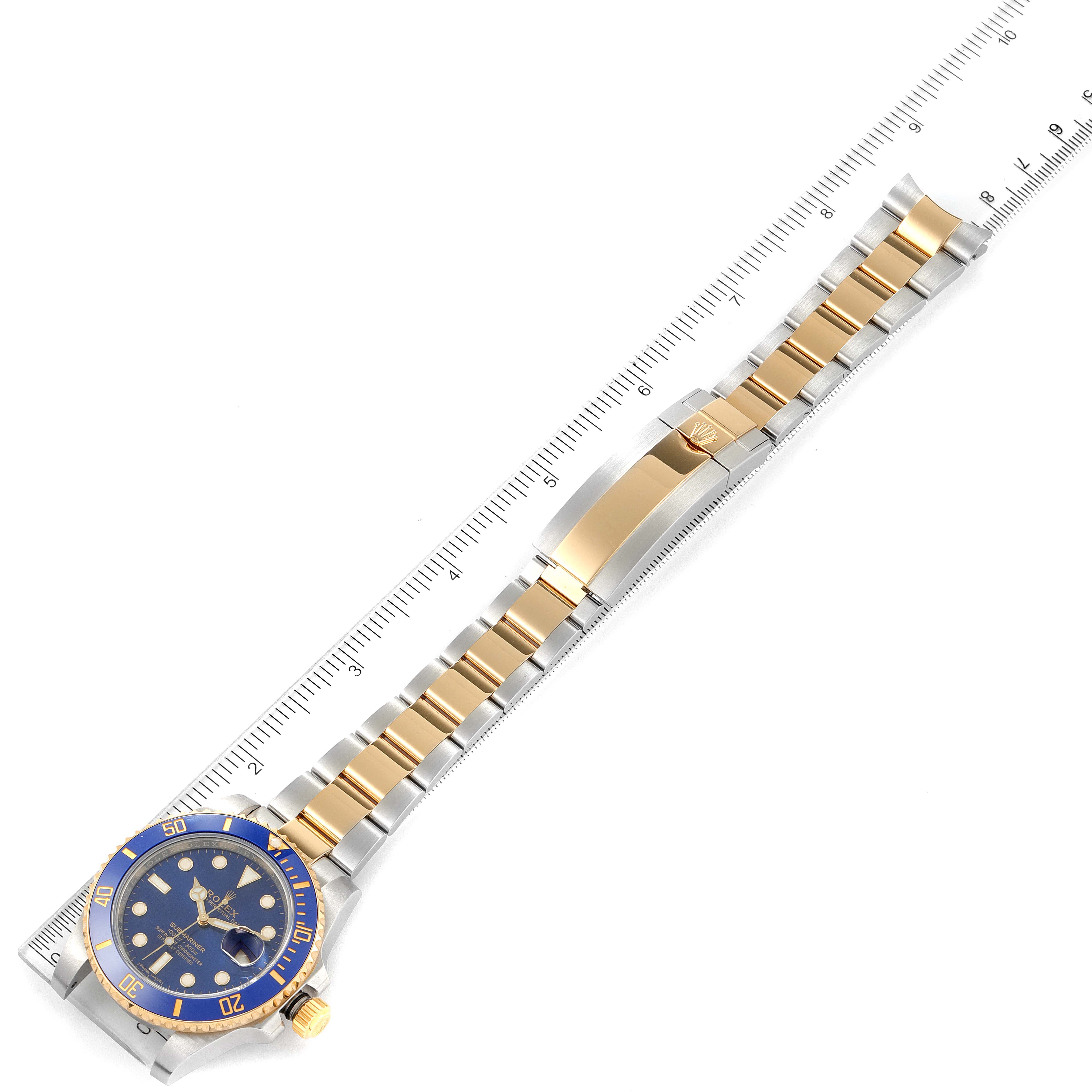 This image shows a top-down view of a Rolex Submariner 116613 Men's Steel and Gold (two tone) Blue Dial 116613 Men's Steel and Gold (two tone) Blue Dial watch, highlighting its bracelet and clasp alongside a ruler for scale.