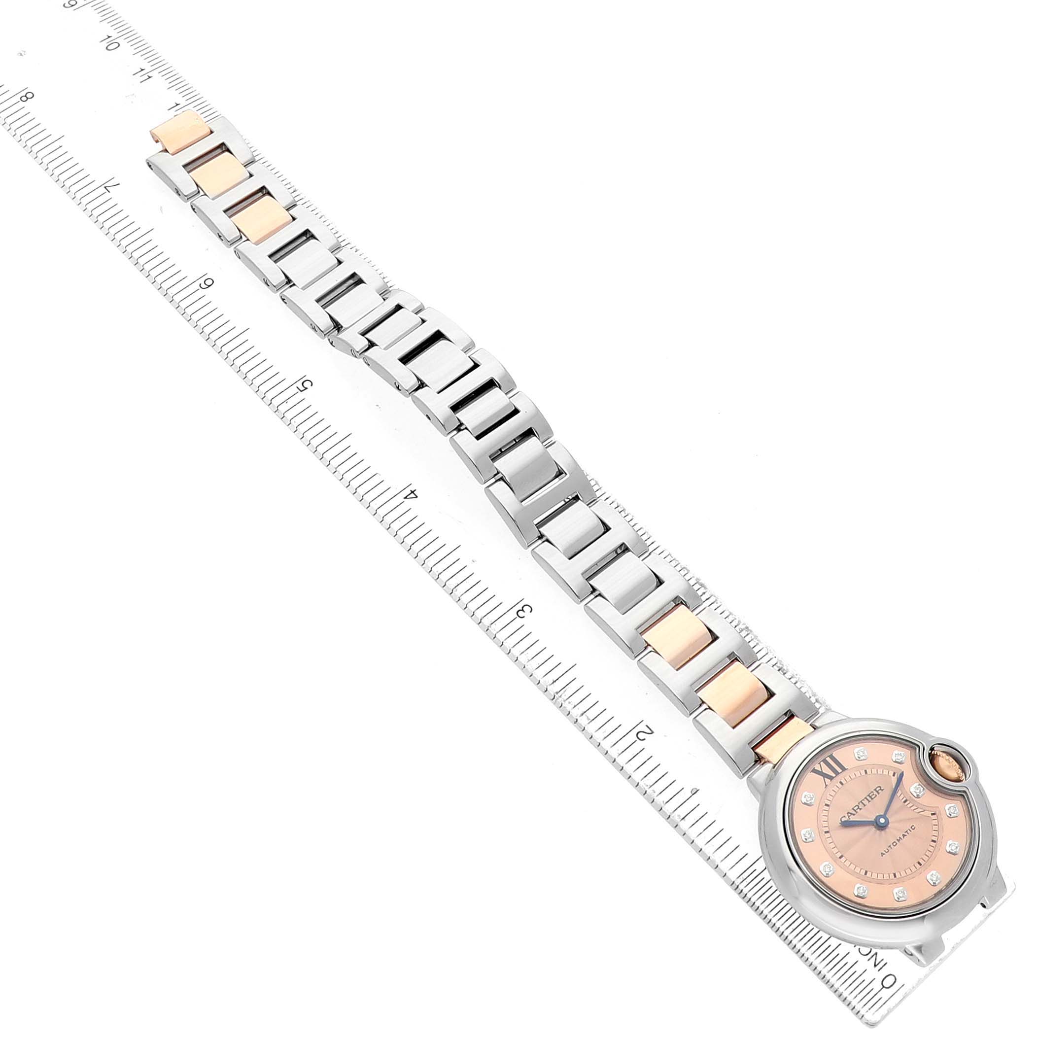 The Cartier Ballon Bleu WE902053 Women's Steel and Gold (two tone) Pink Dial watch is displayed from a top angle, showing the face and the full two-tone bracelet next to a ruler.