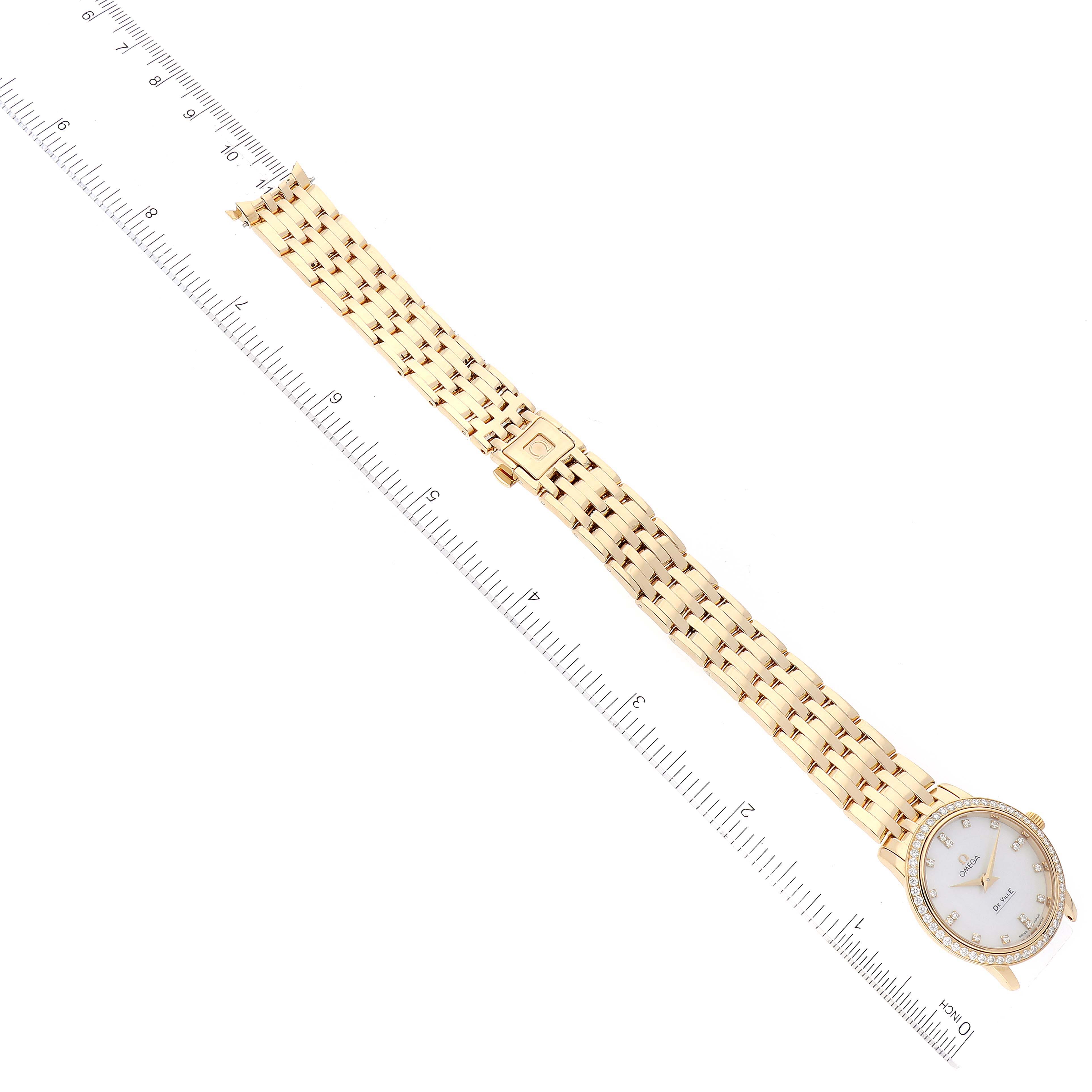 The image shows the Omega 413.55.27.60.55.001 Women's Yellow Gold Mother of Pearl Dial 413.55.27.60.55.001 Women's Yellow Gold Mother of Pearl Dial DeVille Prestige Yellow Gold Diamond Ladies Watch 413.55.27.60.55.001 laid flat with a ruler for scale.