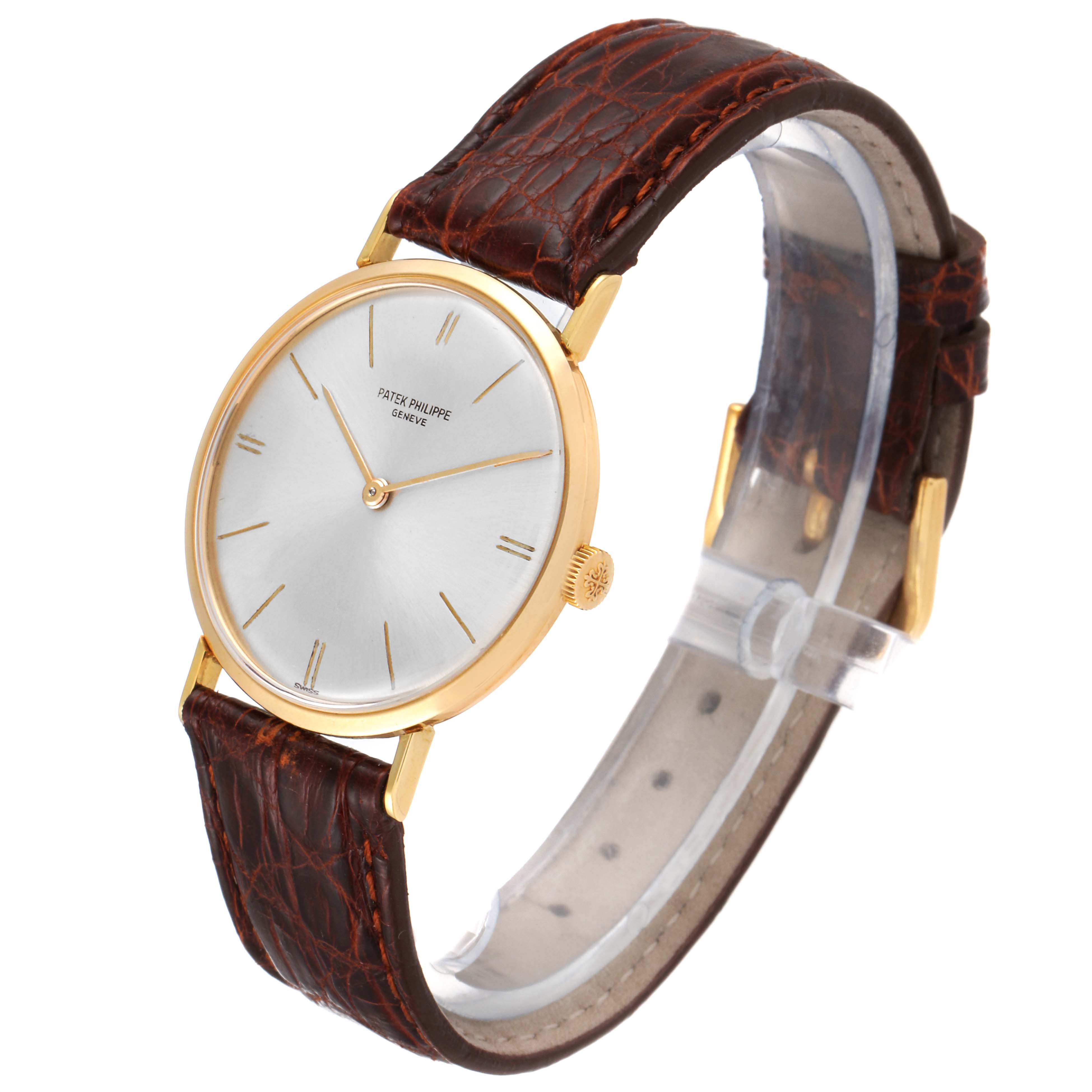 This image shows a vintage Patek Philippe watch at a three-quarter angle, highlighting its face, gold case, and brown leather strap.