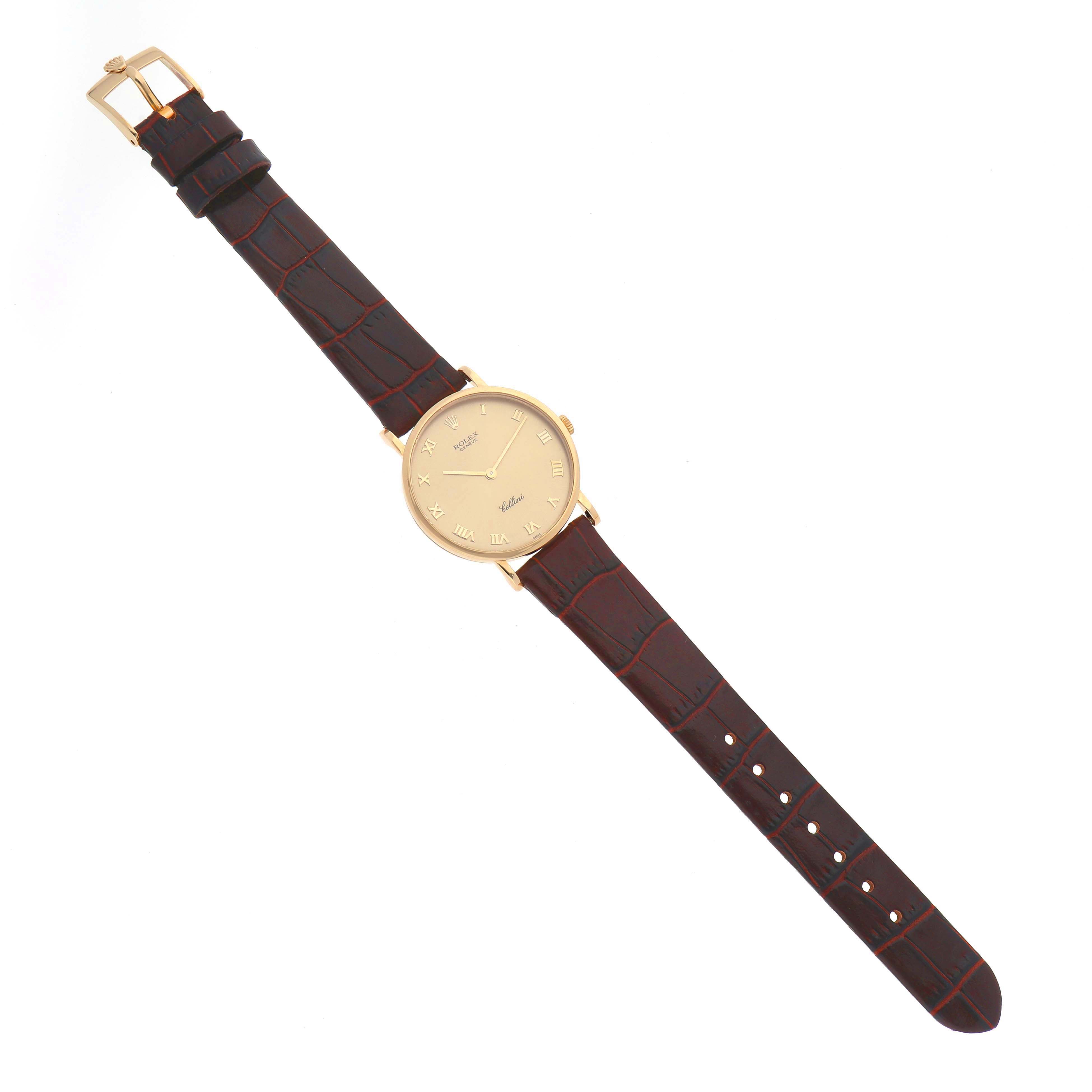 The image shows a top view of a Rolex Cellini 5112 Men
s Yellow Gold Champagne Dial 5112 Men
s Yellow Gold Champagne Dial watch with a gold case and brown leather strap.