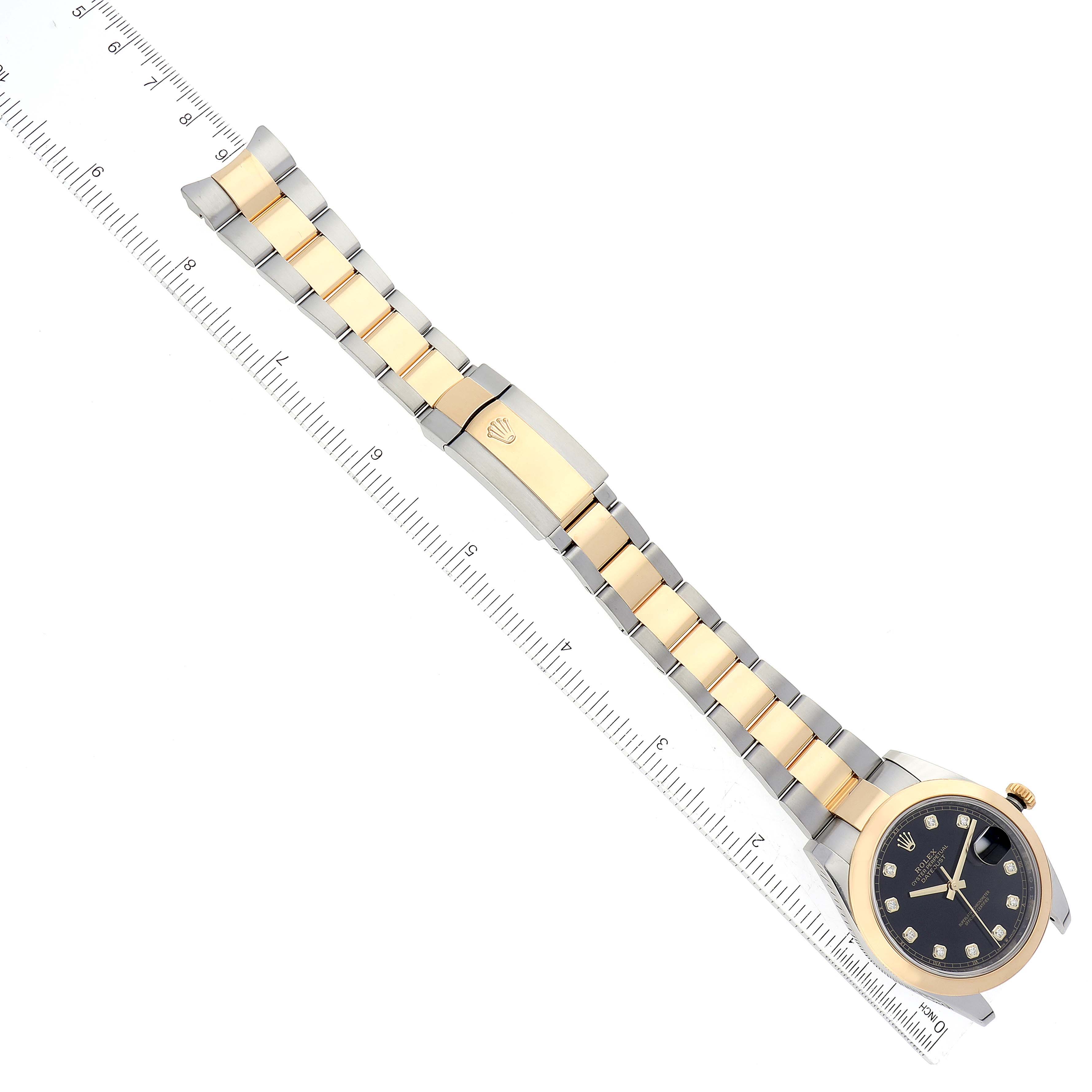 The Rolex Datejust 41 126303 Men's Steel and Gold (two tone) Black Dial 126303 Men's Steel and Gold (two tone) Black Dial watch is shown from an aerial view, displaying its face, bezel, and entire bracelet alongside a ruler.