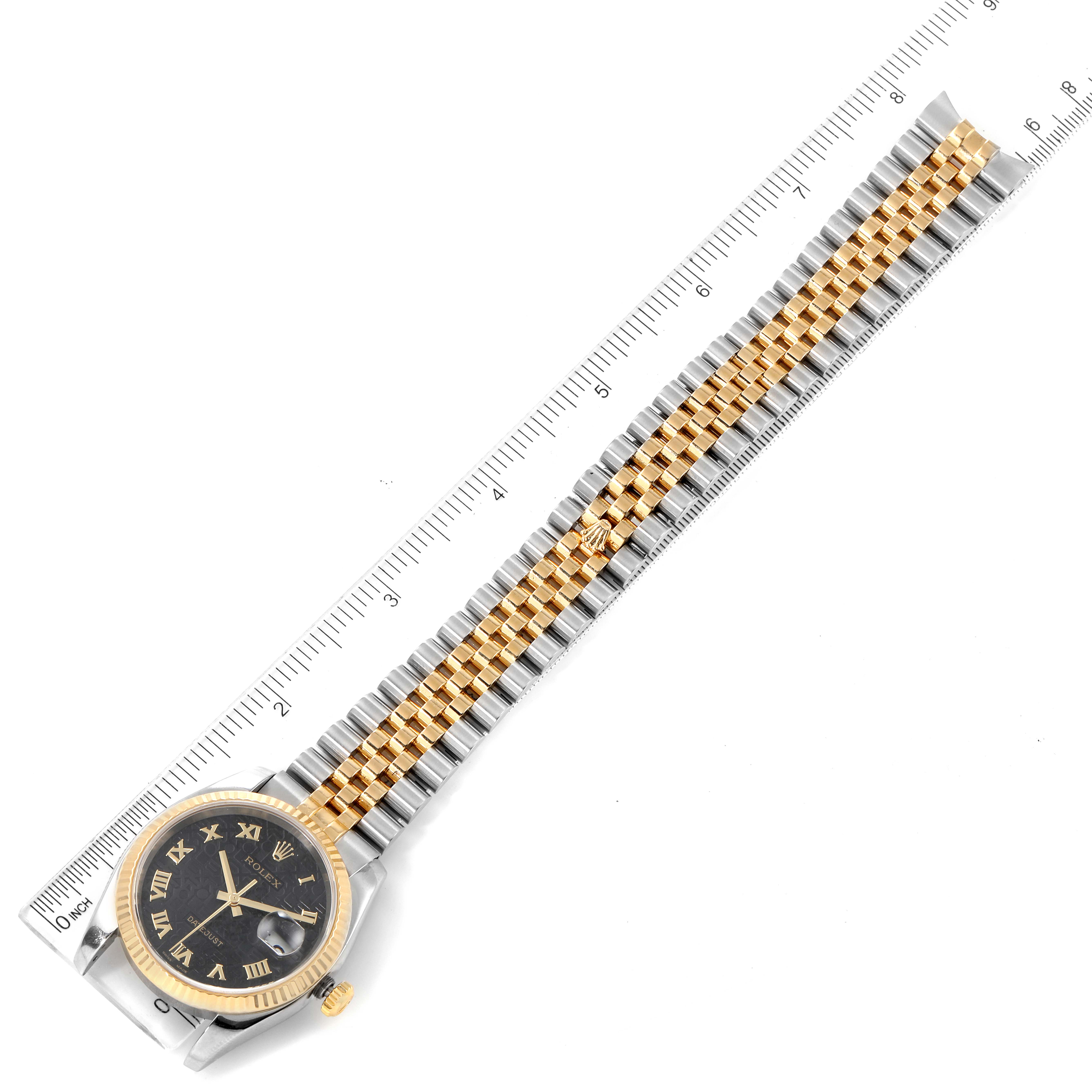 The image shows a Rolex Datejust 116233 Men's Steel and Gold (two tone) Black Dial 116233 Men's Steel and Gold (two tone) Black Dial watch from a top-down angle, displaying the full bracelet and watch face beside a measuring ruler.