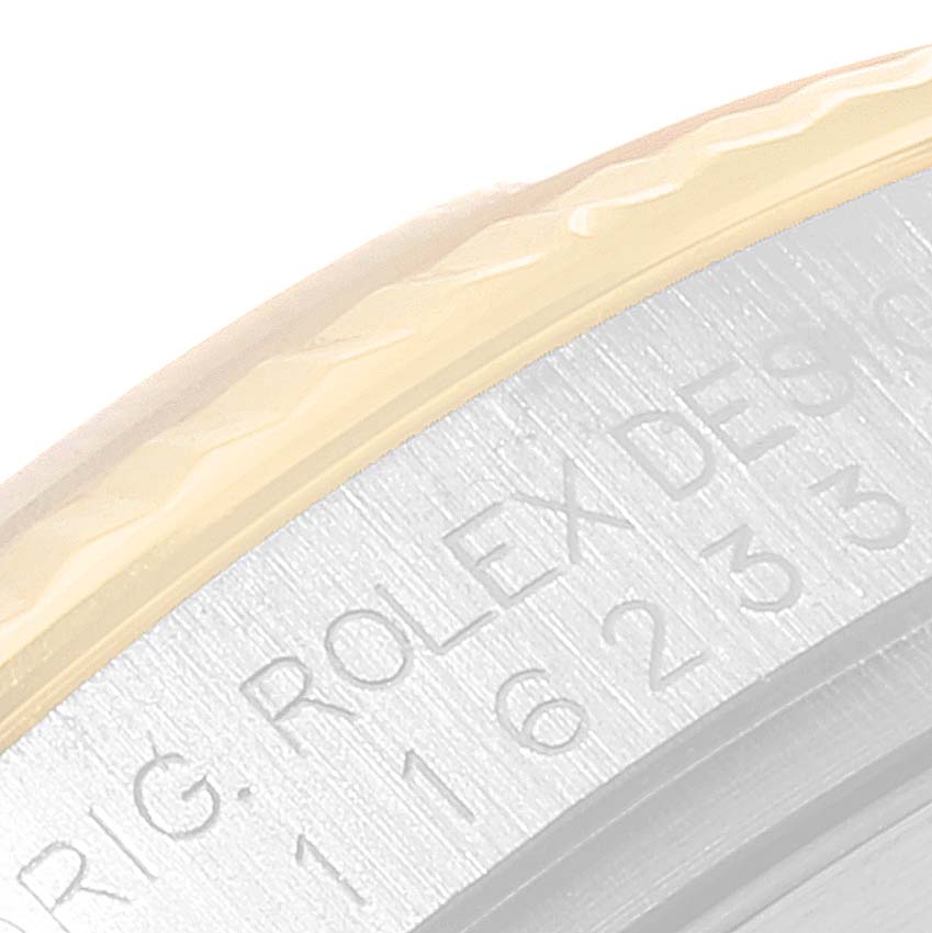 This image shows a close-up angle of the side of a Rolex Datejust 116233 Men's Steel and Gold (two tone) Black Dial 116233 Men's Steel and Gold (two tone) Black Dial watch, specifically the engraved serial number and part of the bezel.