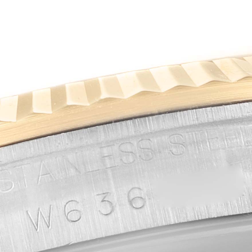 This close-up view of a Rolex Datejust 16233 Men's Steel and Gold (two tone) Champagne Dial 16233 Men's Steel and Gold (two tone) Champagne Dial watch shows the fluted bezel and part of the stainless steel case back with engraved serial numbers.