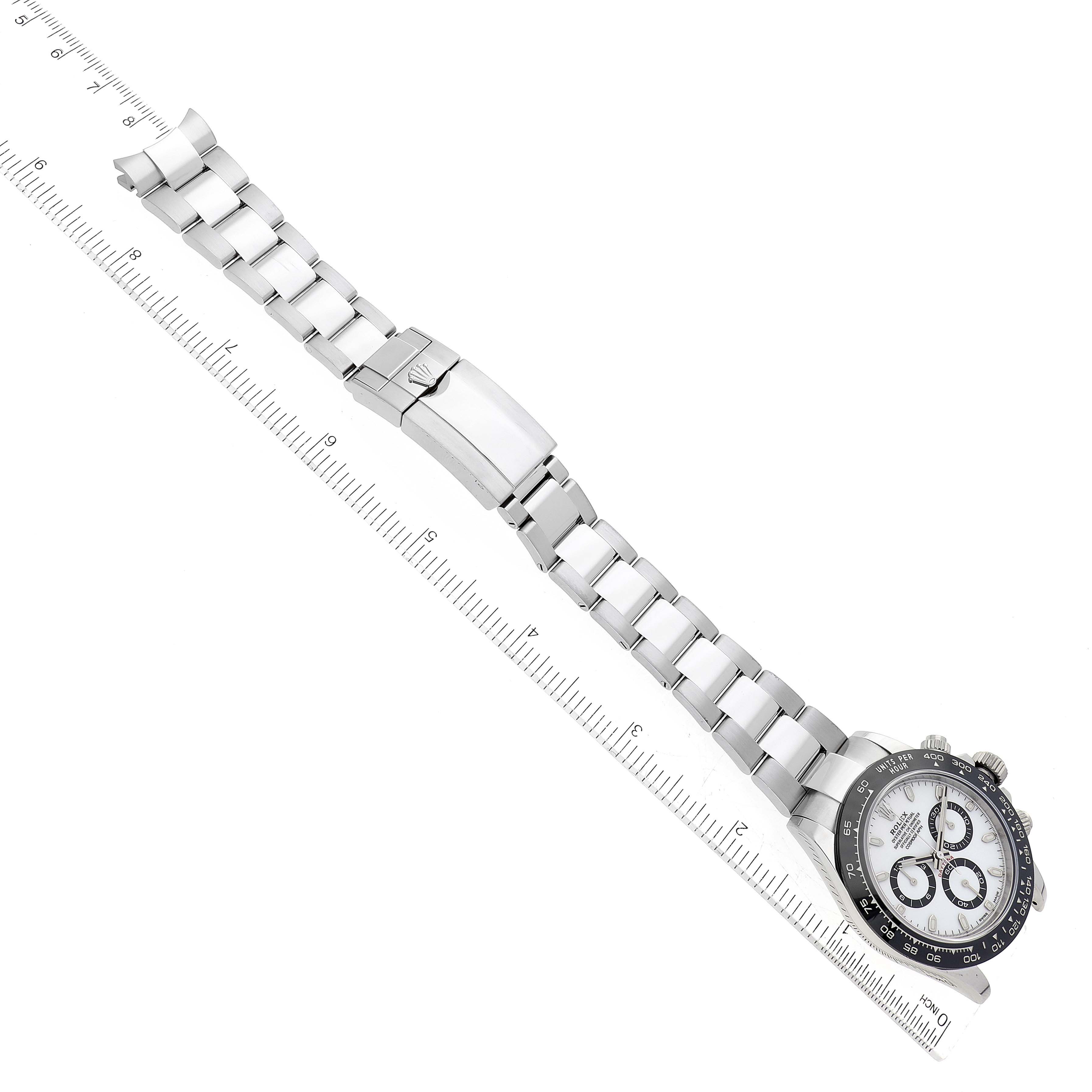 The image shows a top-down view of a Rolex Daytona 116500LN Men's Stainless Steel White Dial 116500LN Men's Stainless Steel White Dial watch, highlighting the bracelet and clasp aligned with a ruler.