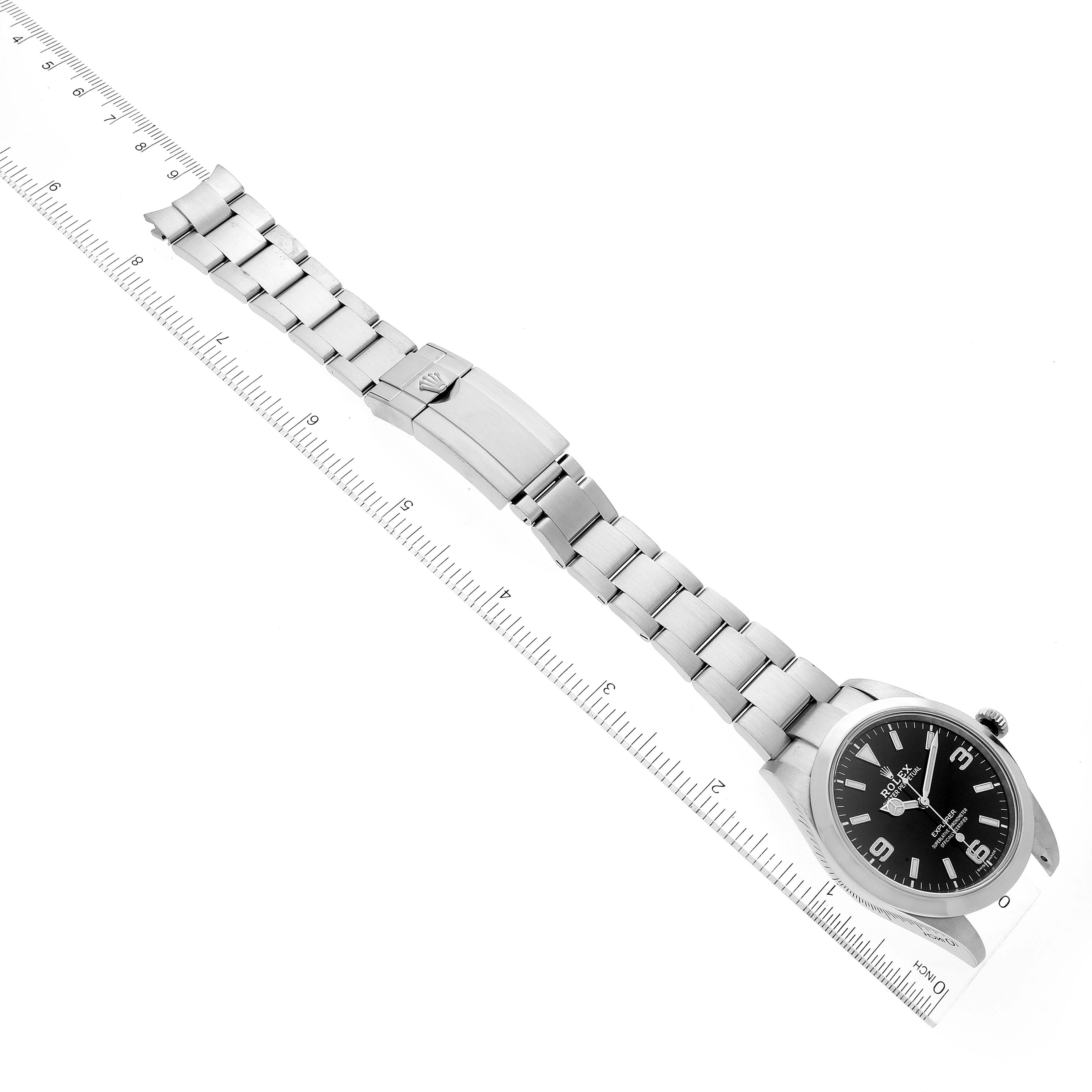 The image shows a Rolex Explorer 214270 Men's Stainless Steel Black Dial 214270 Men's Stainless Steel Black Dial watch laid flat alongside a ruler, displaying the watch face, bracelet, and clasp.