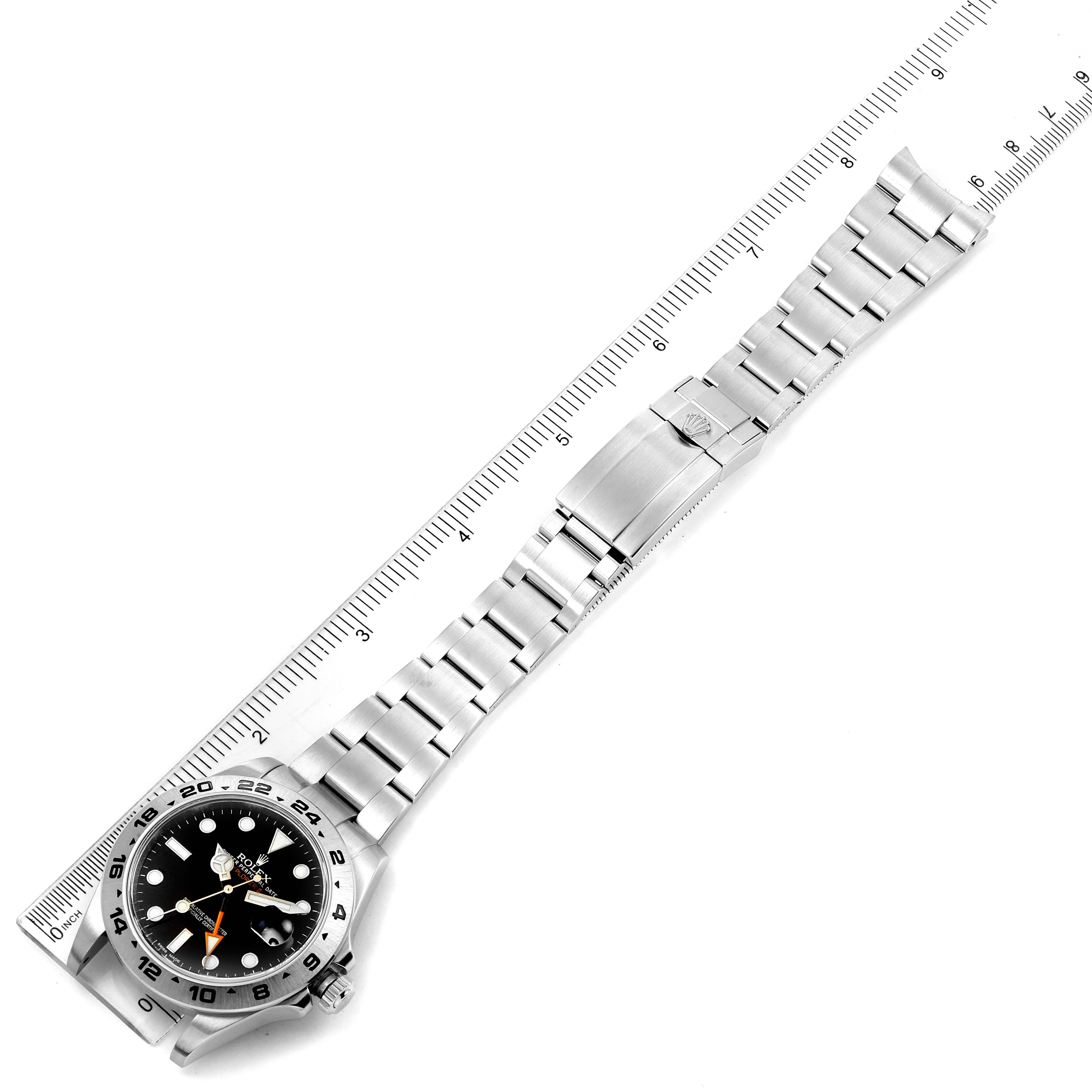 This image shows a Rolex Explorer 216570 Men's Stainless Steel Black Dial 216570 Men's Stainless Steel Black Dial watch laid flat next to a ruler, displaying the face and the full metal band.