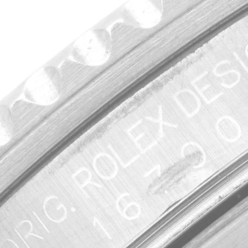 The image shows a close-up of the bezel and engraved side of a Rolex GMT-Master 16700 Men
s Stainless Steel Black Dial 16700 Men
s Stainless Steel Black Dial watch.