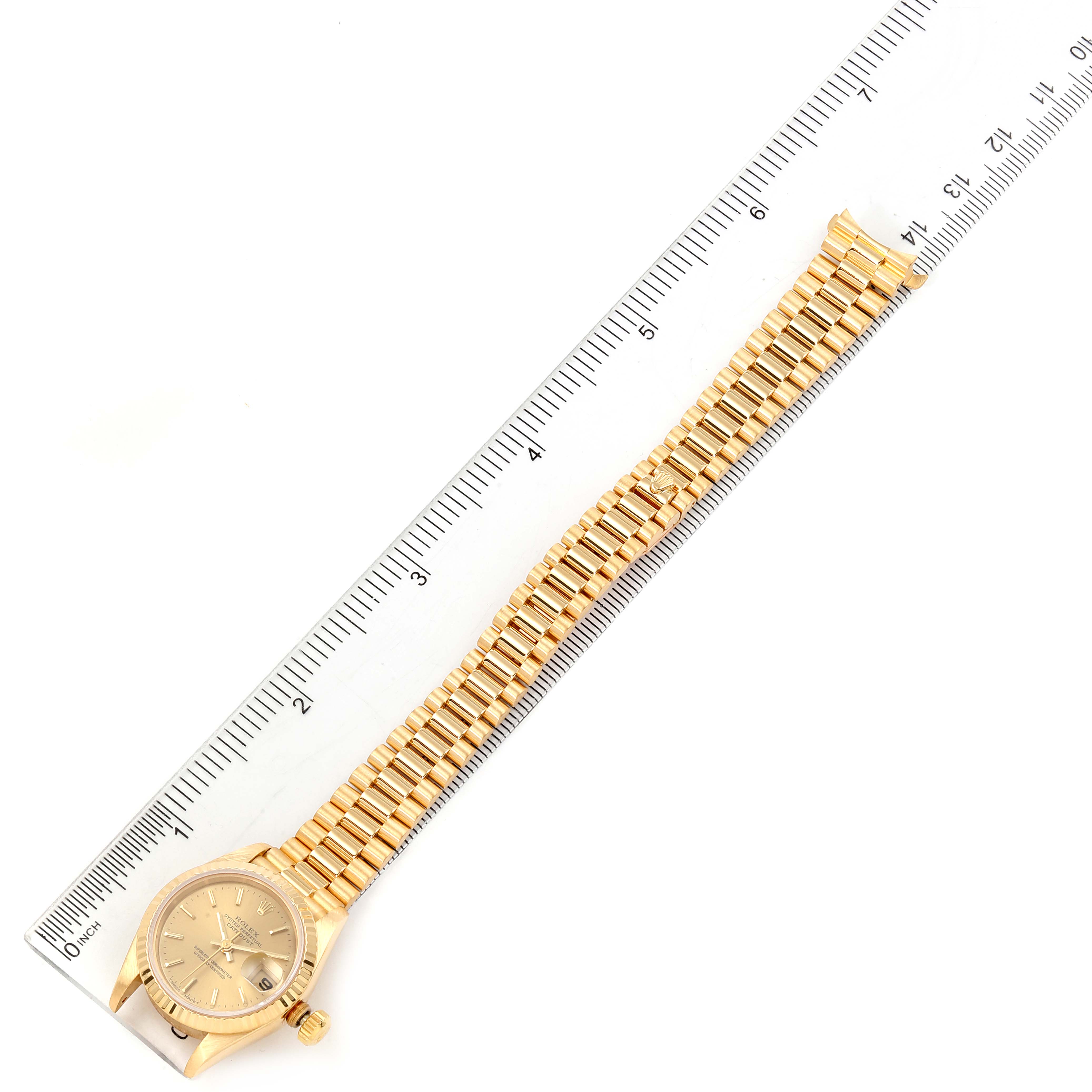 The image shows a gold Rolex President 69178 Women's Yellow Gold Champagne Dial 69178 Women's Yellow Gold Champagne Dial model watch from a top-down angle with its bracelet extended alongside a ruler.