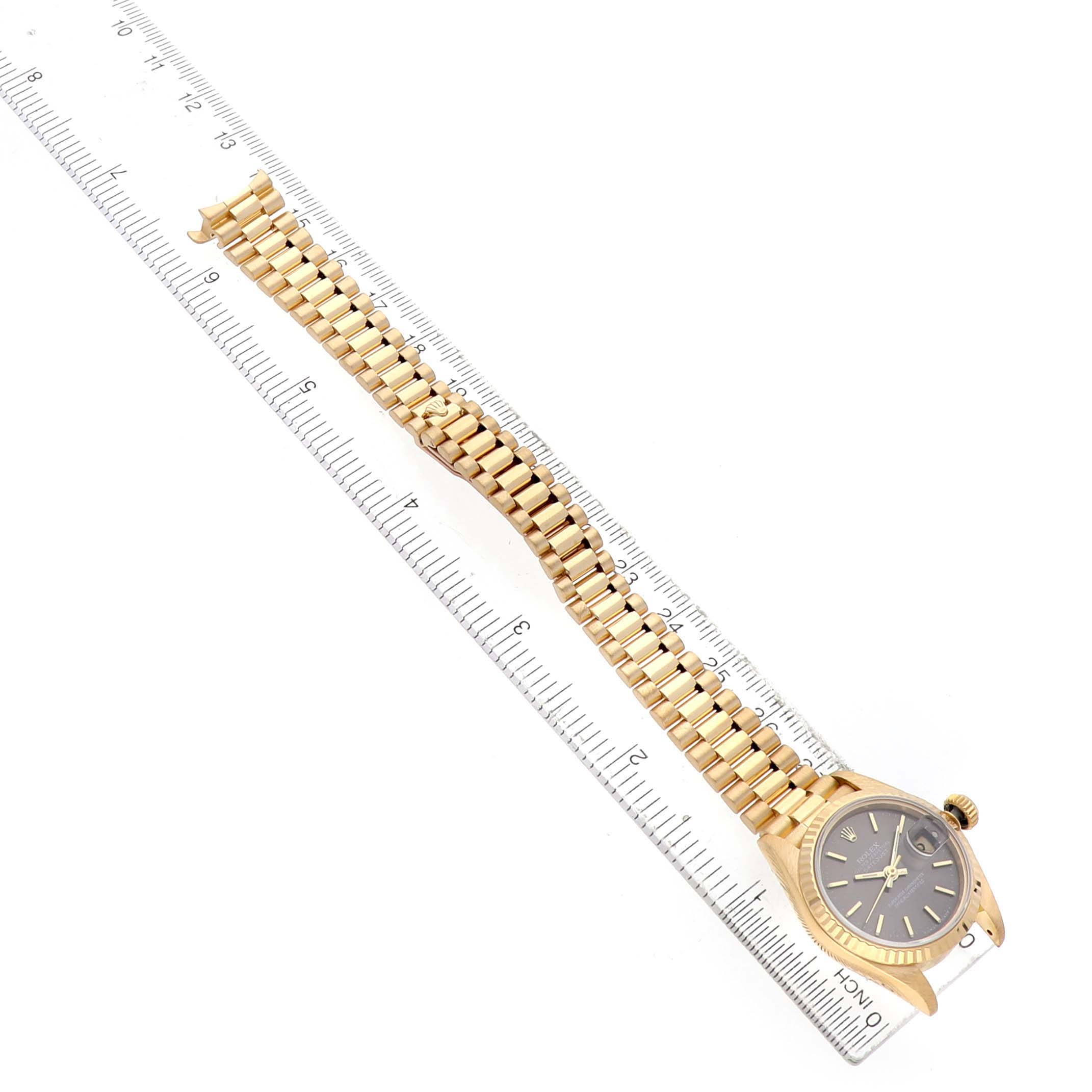 The Rolex President 69178 Women's Yellow Gold Grey Dial model watch is shown from an overhead angle, highlighting the face and entire bracelet beside a ruler.
