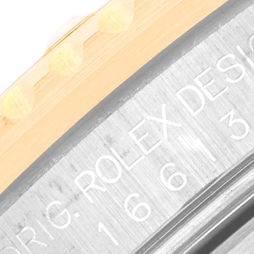 The image shows a close-up of the edge and engravings on a Rolex Submariner 16613LB Men
s Steel and Gold (two tone) Blue Dial 16613LB Men
s Steel and Gold (two tone) Blue Dial watch case.