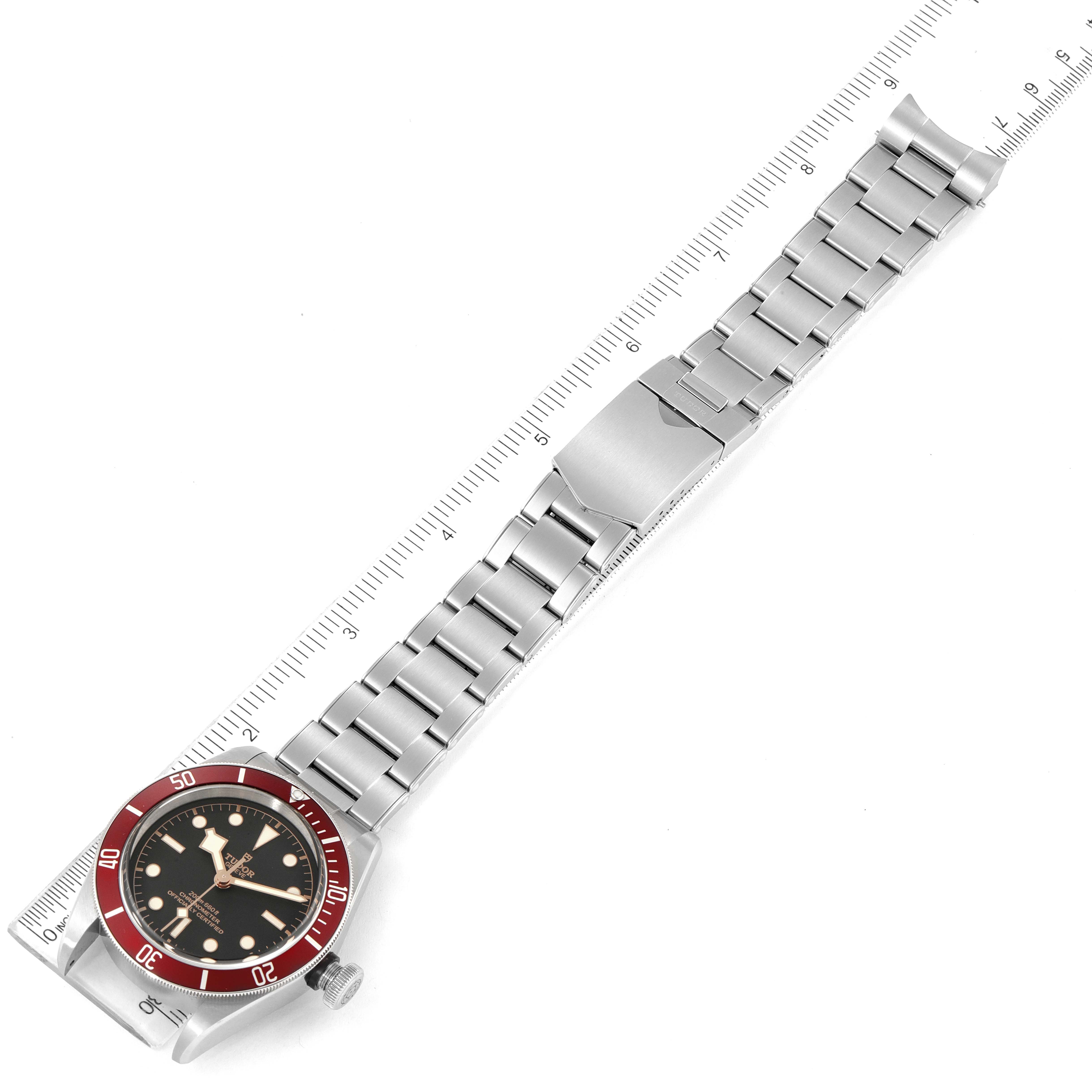 The image shows a Tudor Heritage Black Bay M79230R-0012 Men's Stainless Steel Black Dial M79230R-0012 Men's Stainless Steel Black Dial watch displayed flat, highlighting the bracelet, clasp, and face, alongside a ruler.