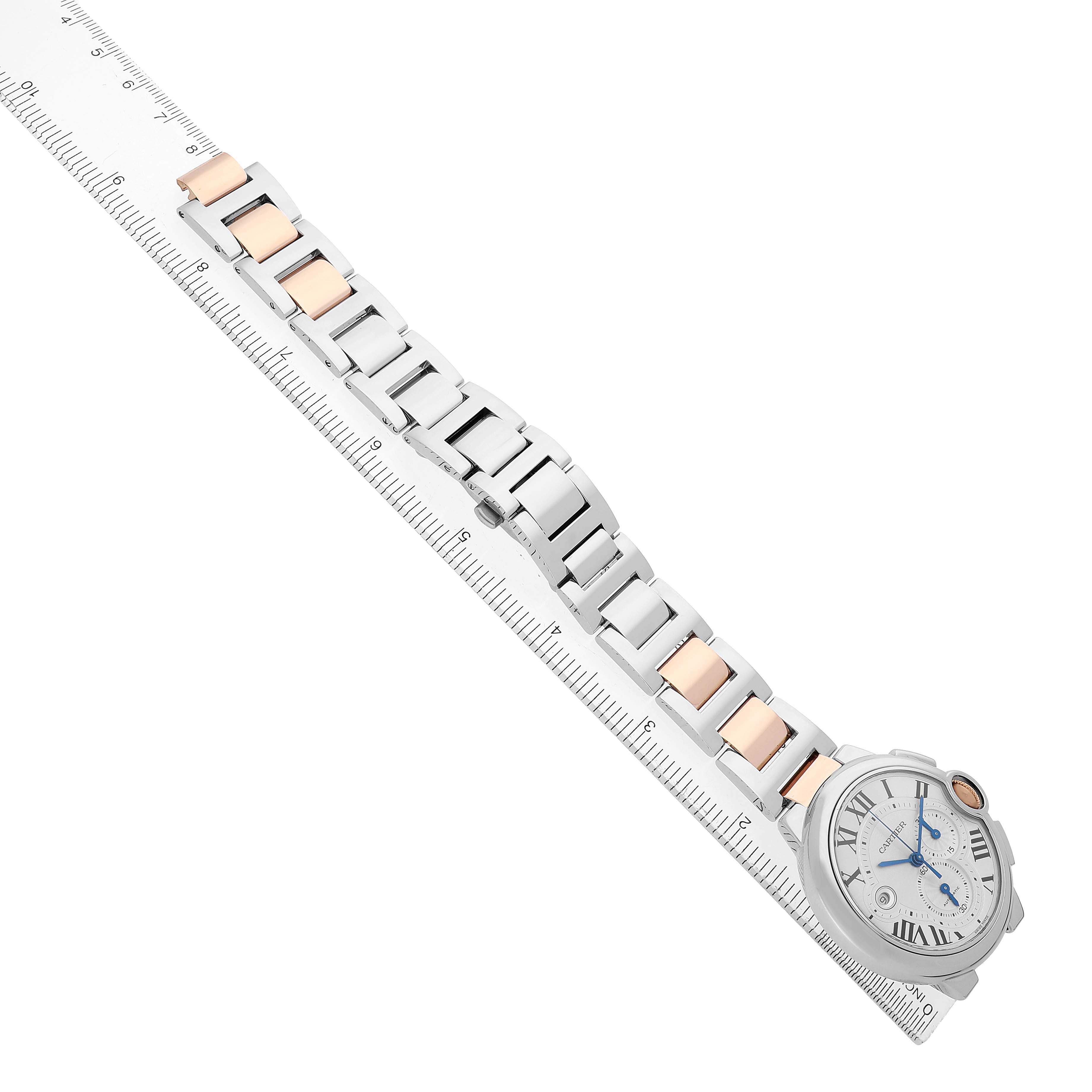 The Cartier Ballon Bleu W6920063 Men's Steel and Gold (two tone) Silver Dial watch is shown from a top angle, featuring its face and two-tone bracelet next to a ruler.