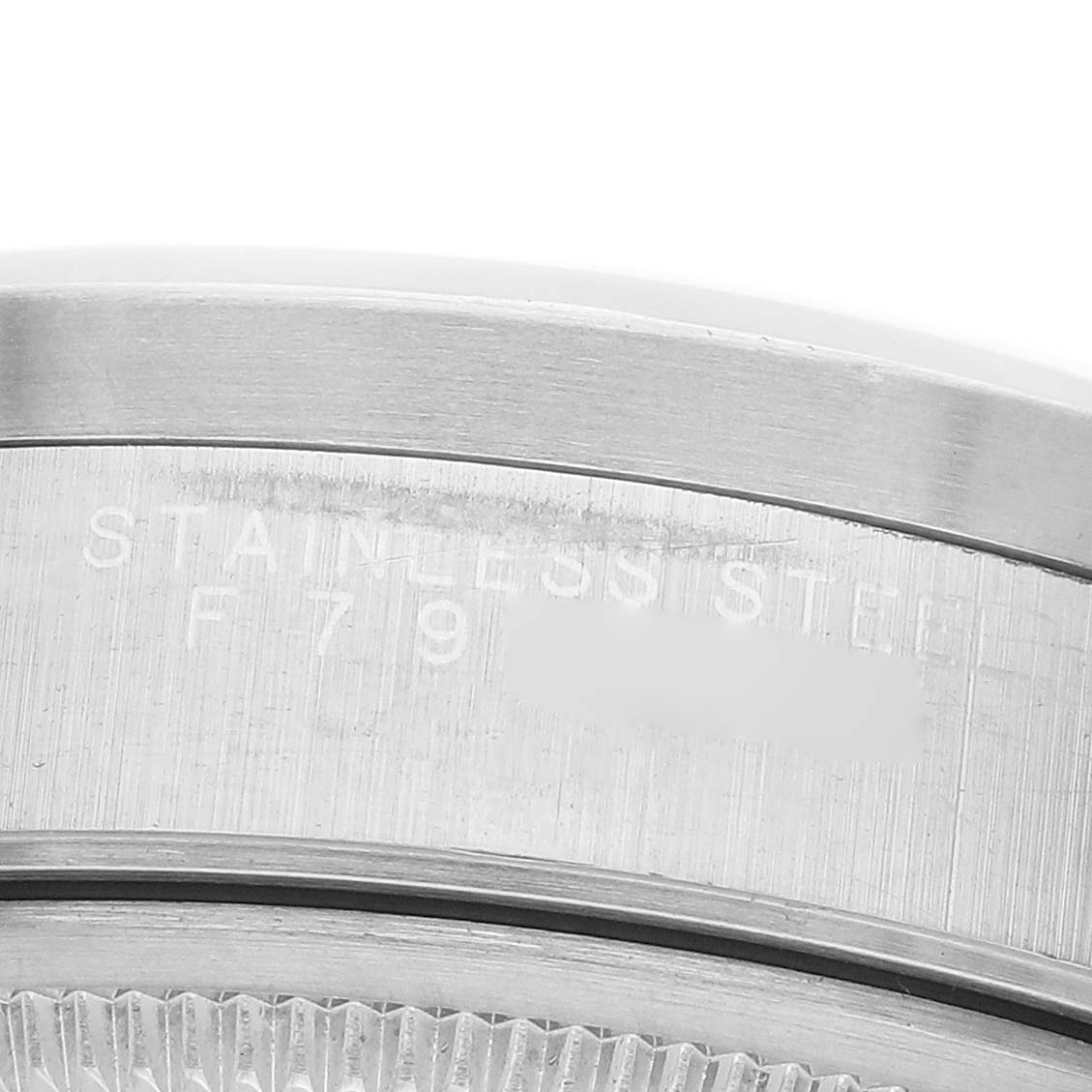 The image shows a close-up of the side of a Rolex Date 15210 Men's Stainless Steel Silver Dial watch case, focusing on the stainless steel engraving.