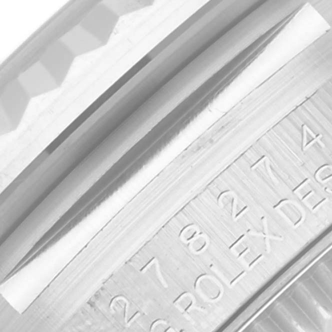 The image shows a close-up of the side and edge details of a Mid-Size Rolex watch, featuring part of the bezel and engraved text.